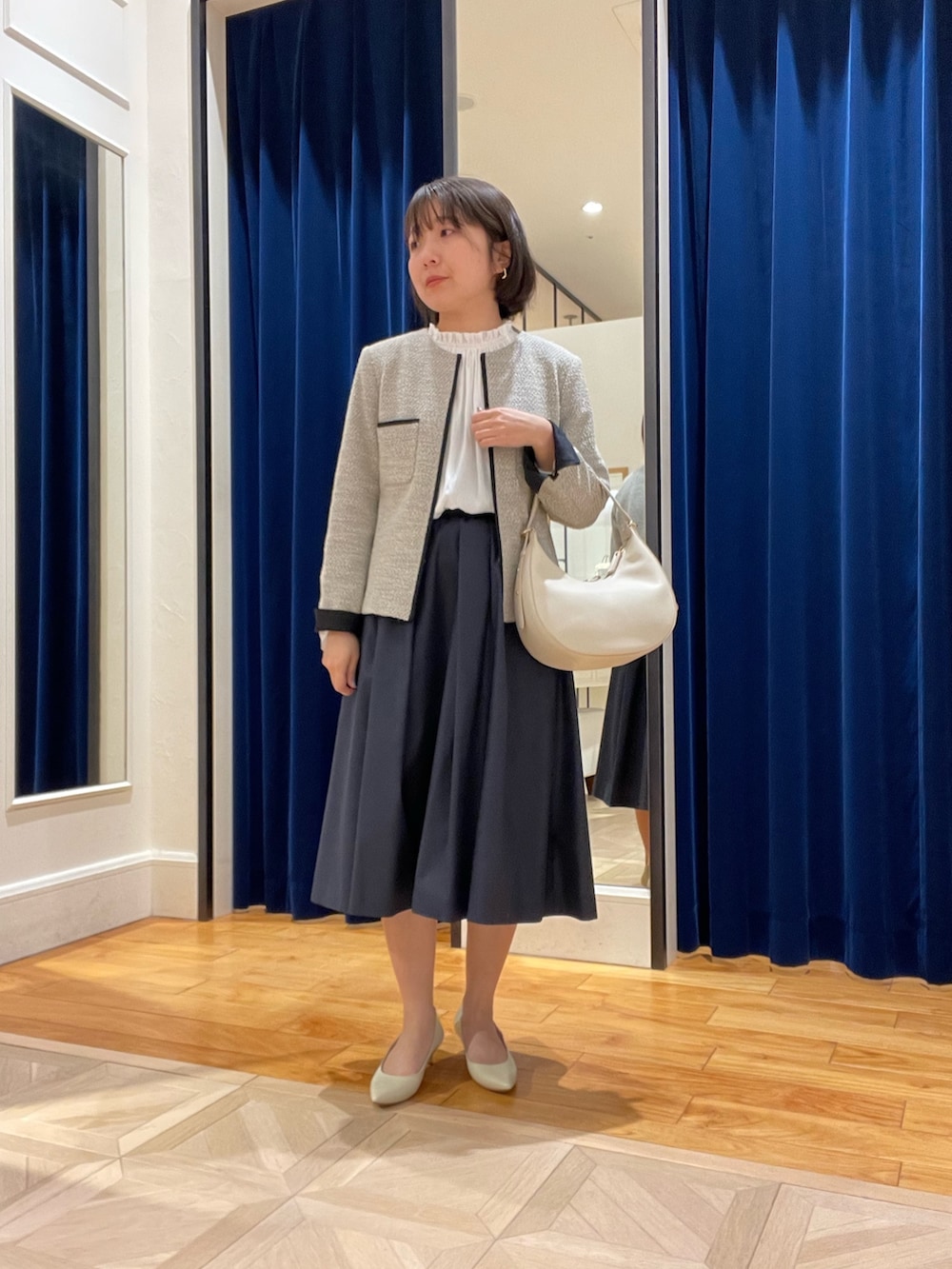 ベージュ系のノーカラージャケット、ブルー系のスカート、ホワイト系のシャツ/ブラウスを着用したレディースの冬コーディネートの2枚目の写真