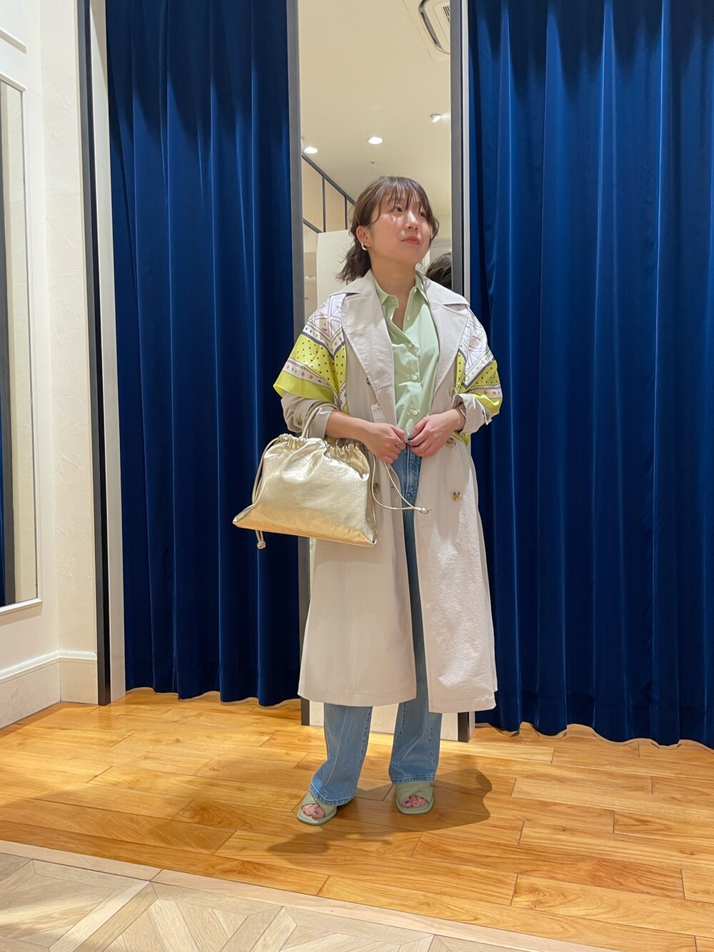 ベージュ系のトレンチコート、ブルー系のデニムパンツ、グリーン系のシャツ/ブラウスを着用したレディースの春コーディネートの3枚目の写真