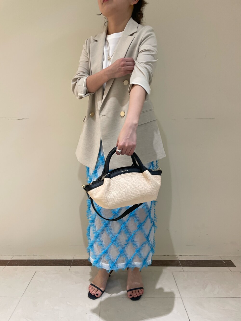 ベージュ系のテーラードジャケット、ブルー系のスカート、ホワイト系のTシャツ/カットソーを着用したレディースの春コーディネートの5枚目の写真