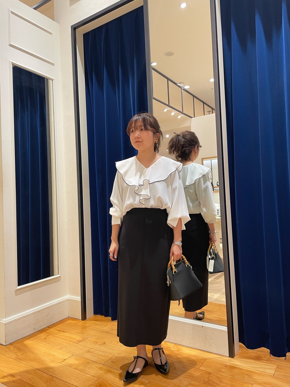 ホワイト系のシャツ/ブラウス、ブラック系のスカート、ゴールド系のパンプスを着用したレディースの春コーディネートの2枚目の写真