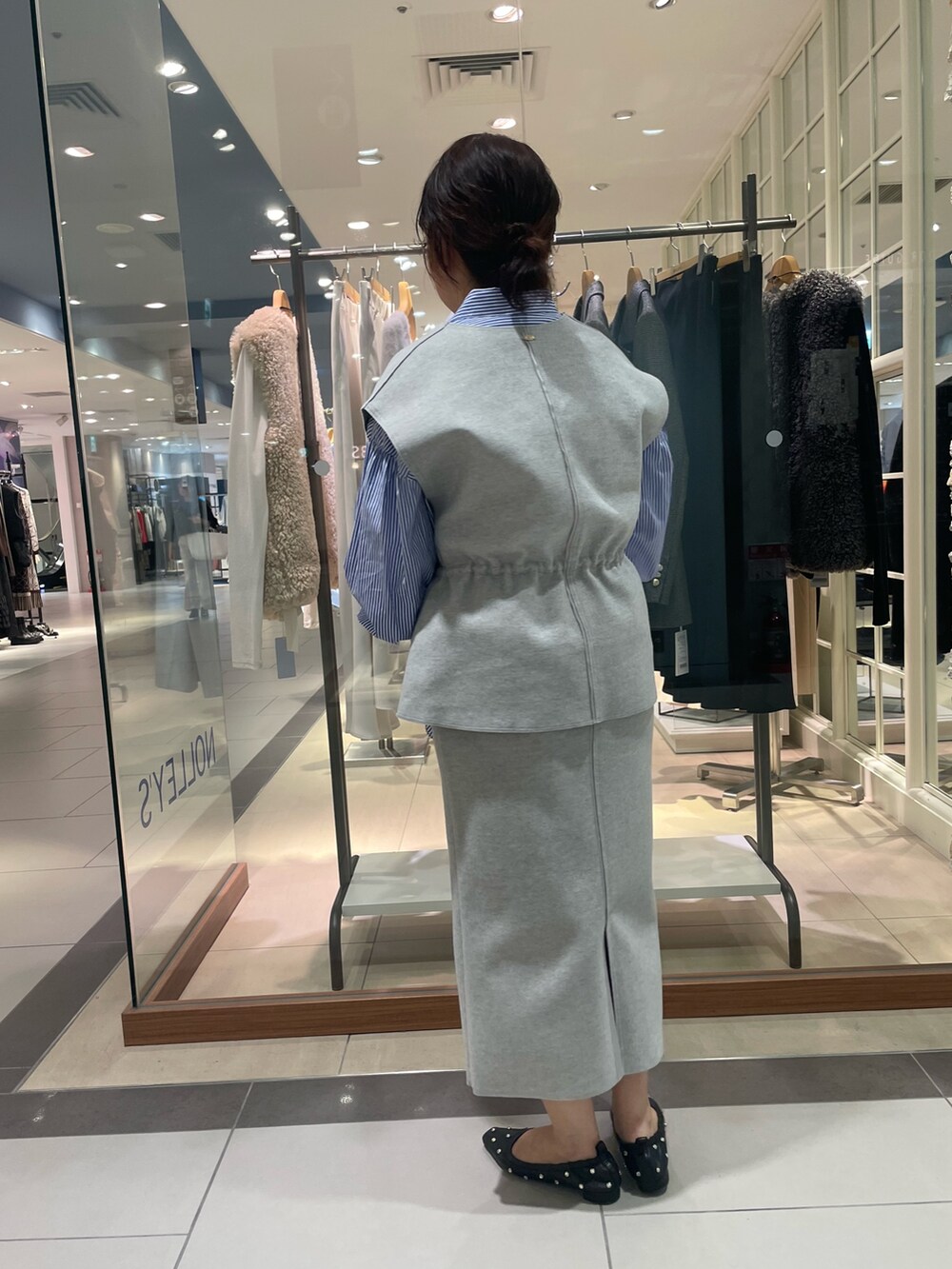 グレー系のベスト、グレー系のスカート、ブルー系のシャツ/ブラウスを着用したレディースの秋コーディネートの4枚目の写真