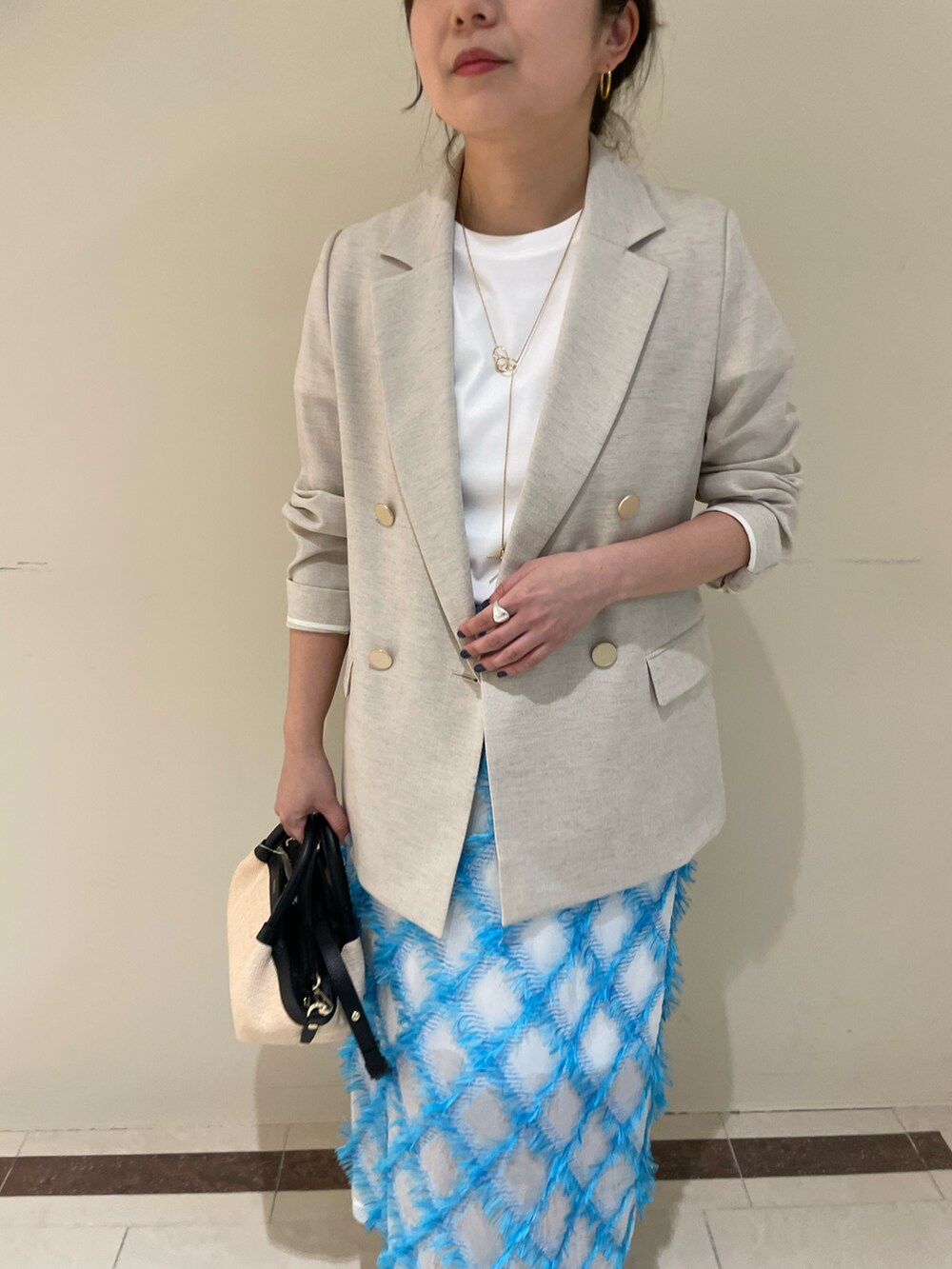 ベージュ系のテーラードジャケット、ブルー系のスカート、ホワイト系のTシャツ/カットソーを着用したレディースの春コーディネートの6枚目の写真