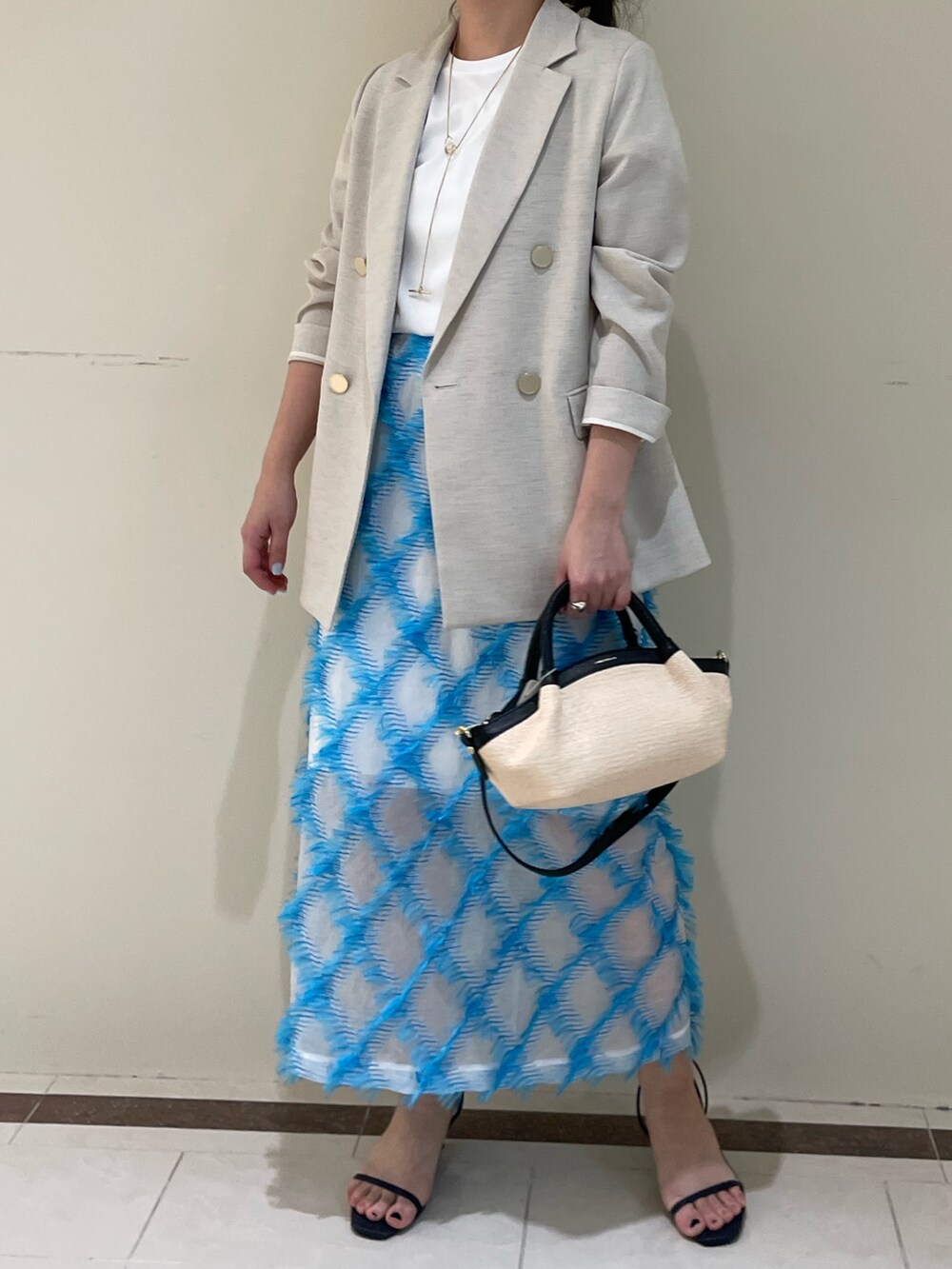 ベージュ系のテーラードジャケット、ブルー系のスカート、ホワイト系のTシャツ/カットソーを着用したレディースの春コーディネートの2枚目の写真