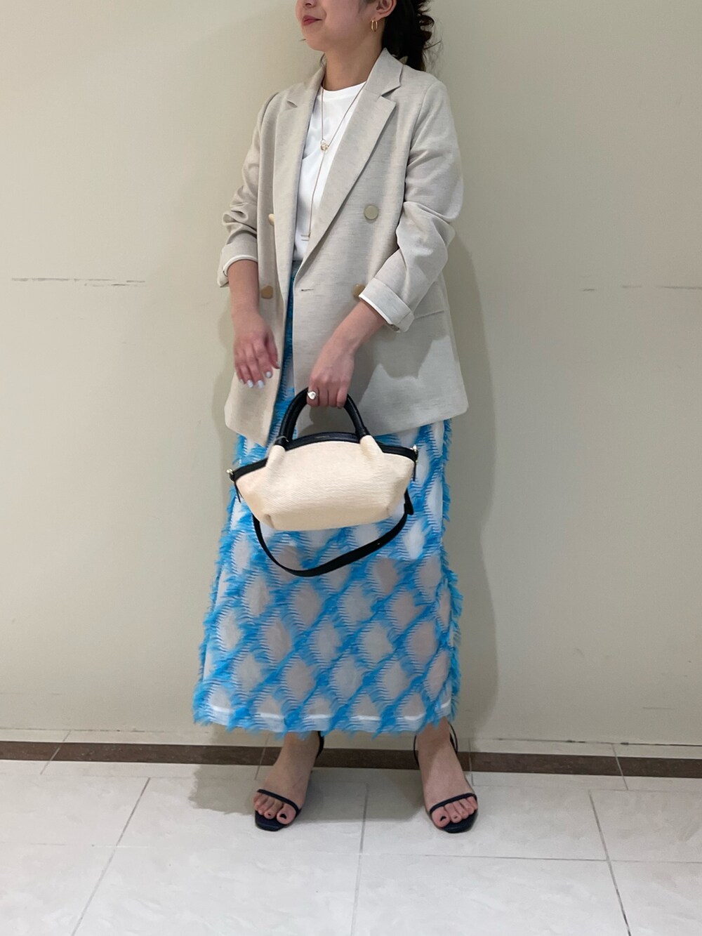 ベージュ系のテーラードジャケット、ブルー系のスカート、ホワイト系のTシャツ/カットソーを着用したレディースの春コーディネートの3枚目の写真