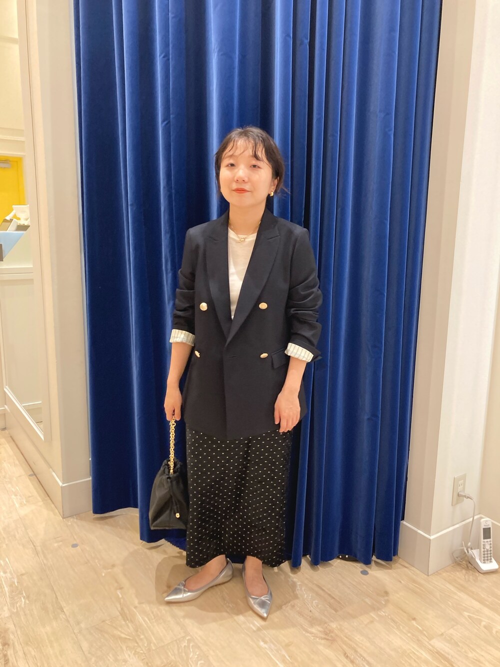 ブルー系のテーラードジャケット、ブラック系のスカート、ホワイト系のTシャツ/カットソーを着用したレディースの秋コーディネートの2枚目の写真