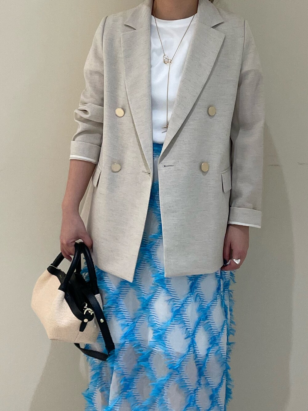 ベージュ系のテーラードジャケット、ブルー系のスカート、ホワイト系のTシャツ/カットソーを着用したレディースの春コーディネートの4枚目の写真