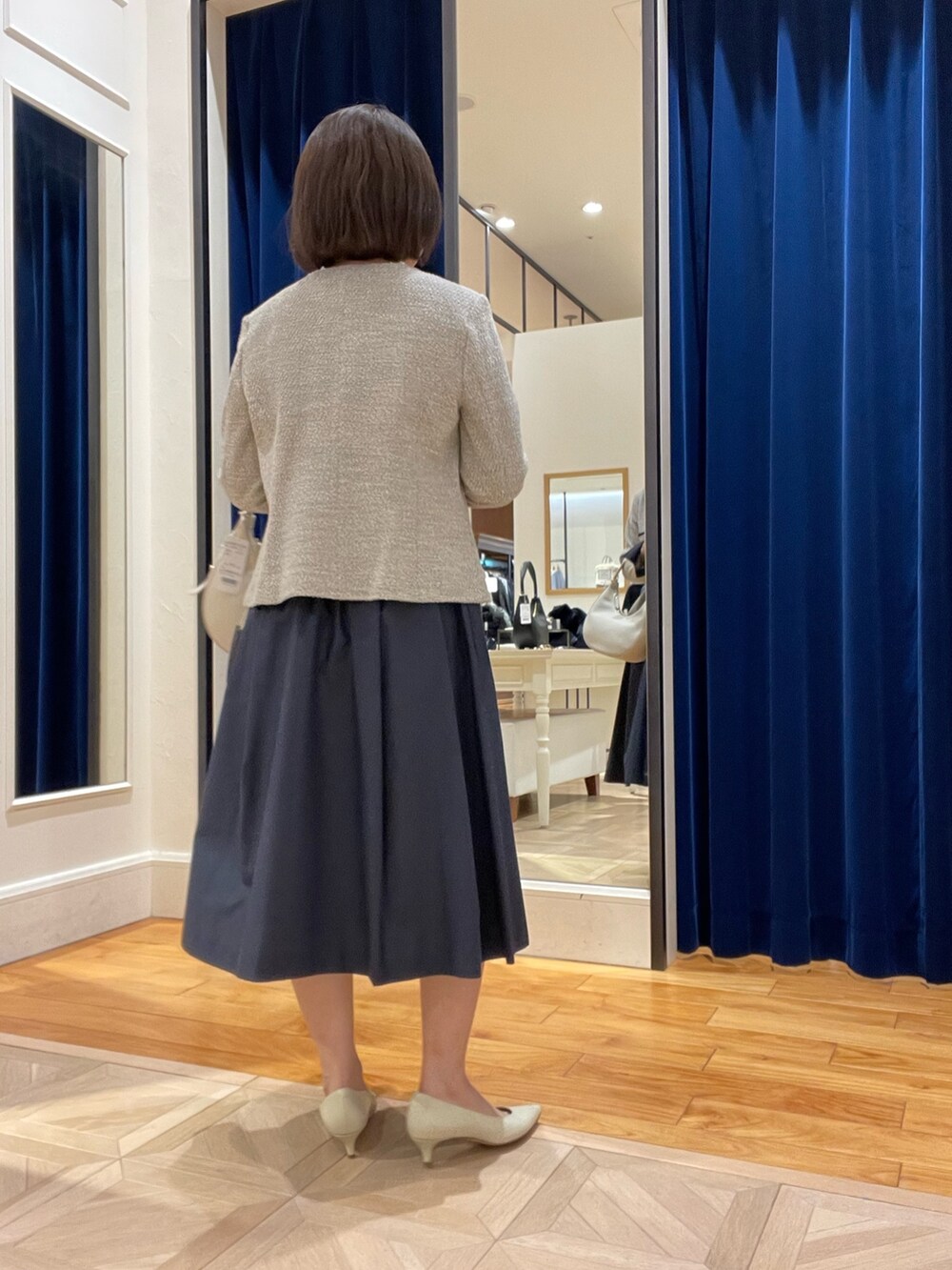 ベージュ系のノーカラージャケット、ブルー系のスカート、ホワイト系のシャツ/ブラウスを着用したレディースの冬コーディネートの3枚目の写真