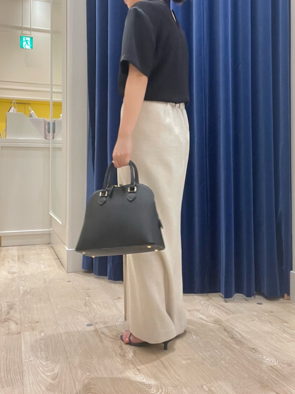 ベージュ系のスカート、ブラック系のシャツ/ブラウス、ブラック系のボストンバッグを着用したレディースの春コーディネートの3枚目の写真