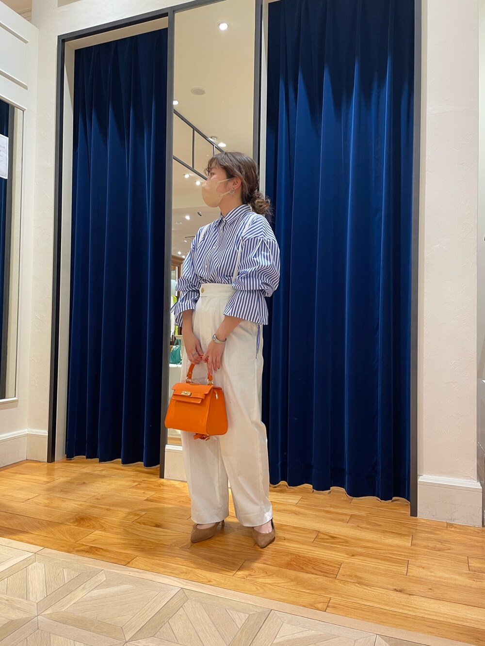 ブルー系のシャツ/ブラウス、ホワイト系のその他パンツ、オレンジ系のショルダーバッグを着用したレディースの春コーディネートの4枚目の写真