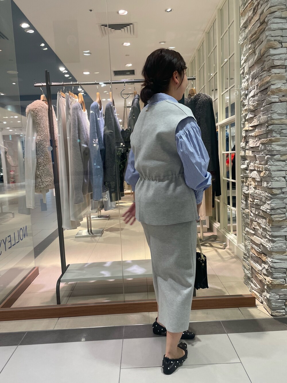 グレー系のベスト、グレー系のスカート、ブルー系のシャツ/ブラウスを着用したレディースの秋コーディネートの3枚目の写真