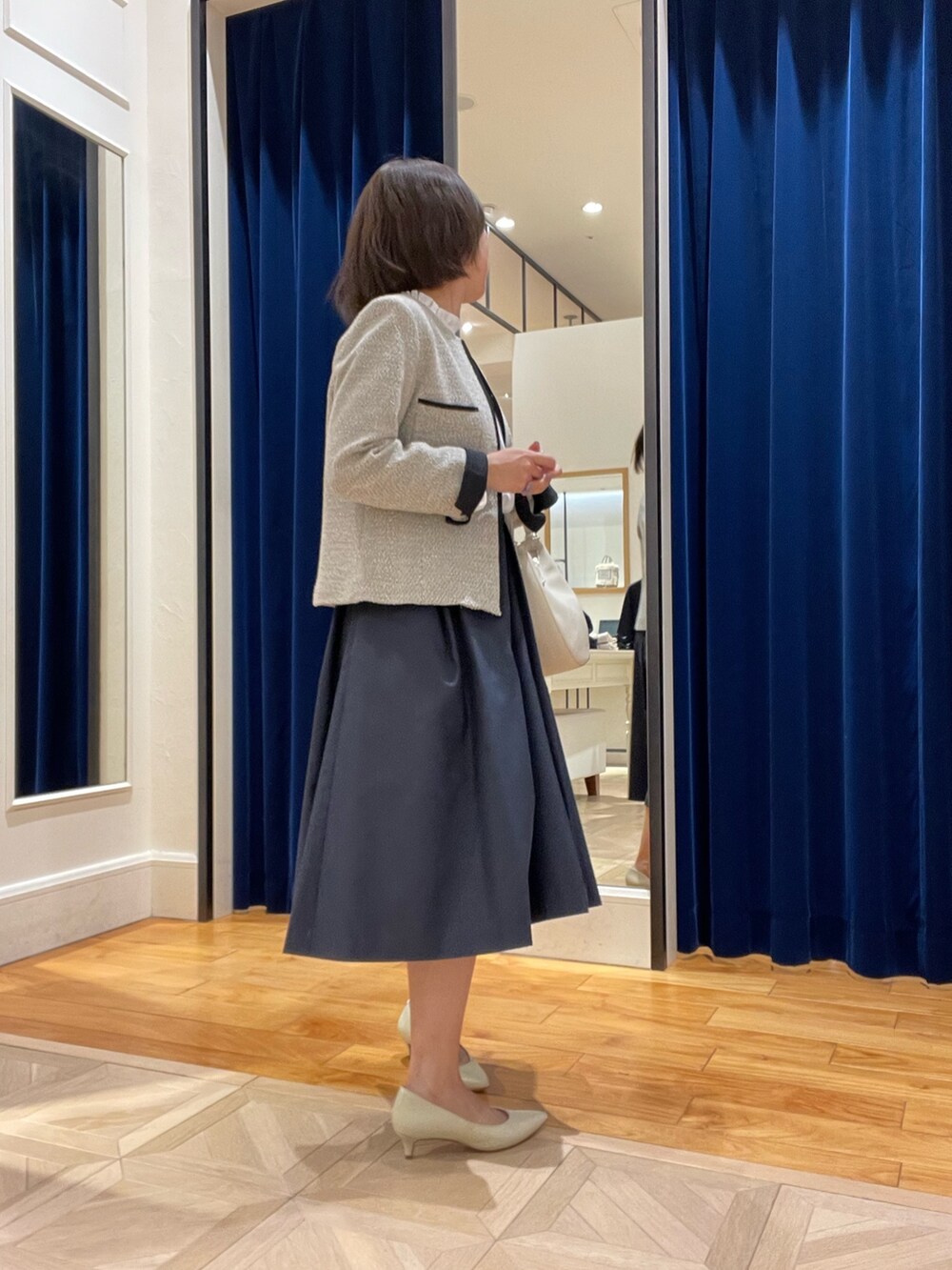 ベージュ系のノーカラージャケット、ブルー系のスカート、ホワイト系のシャツ/ブラウスを着用したレディースの冬コーディネートの4枚目の写真