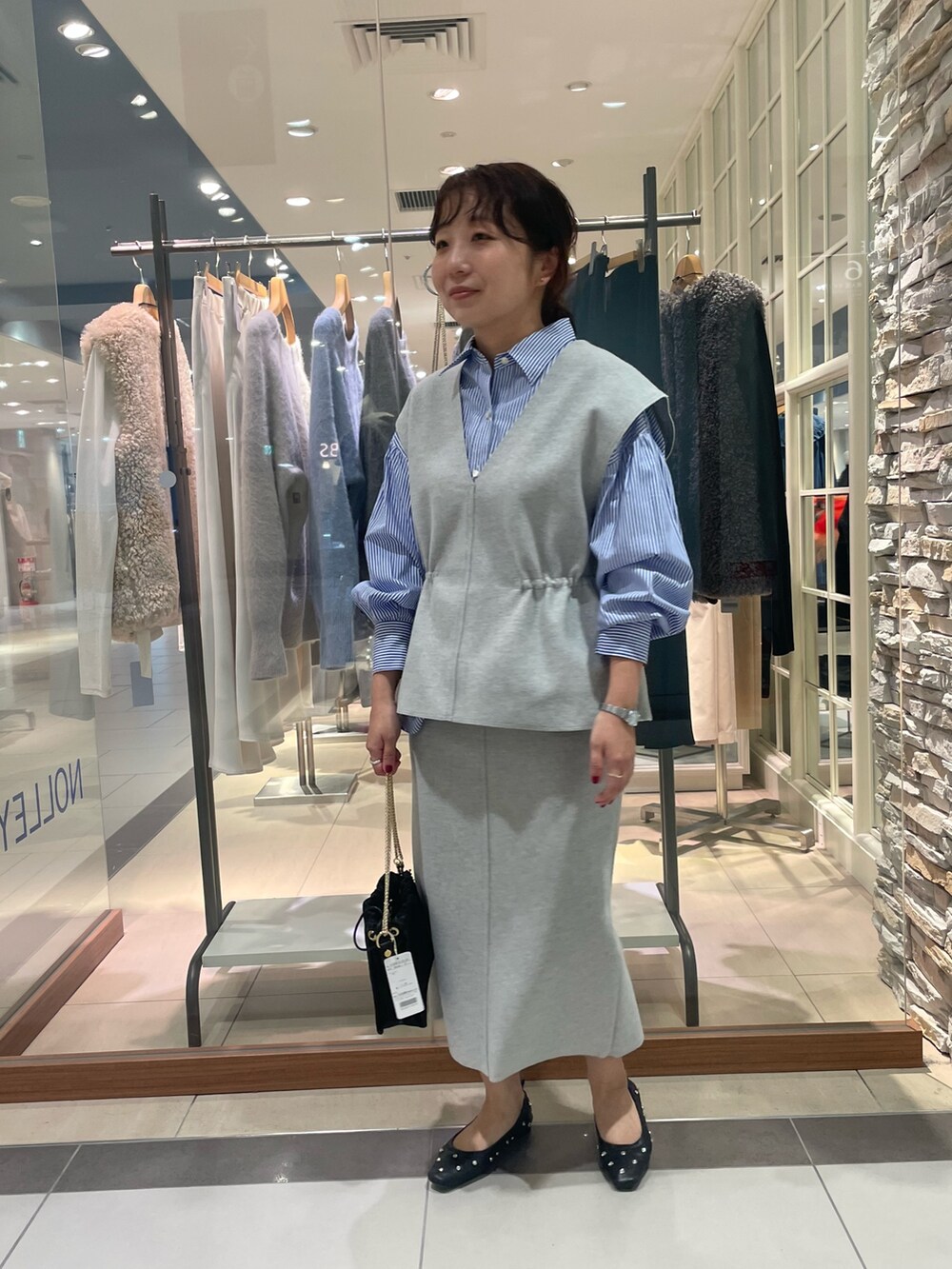 グレー系のベスト、グレー系のスカート、ブルー系のシャツ/ブラウスを着用したレディースの秋コーディネートの2枚目の写真