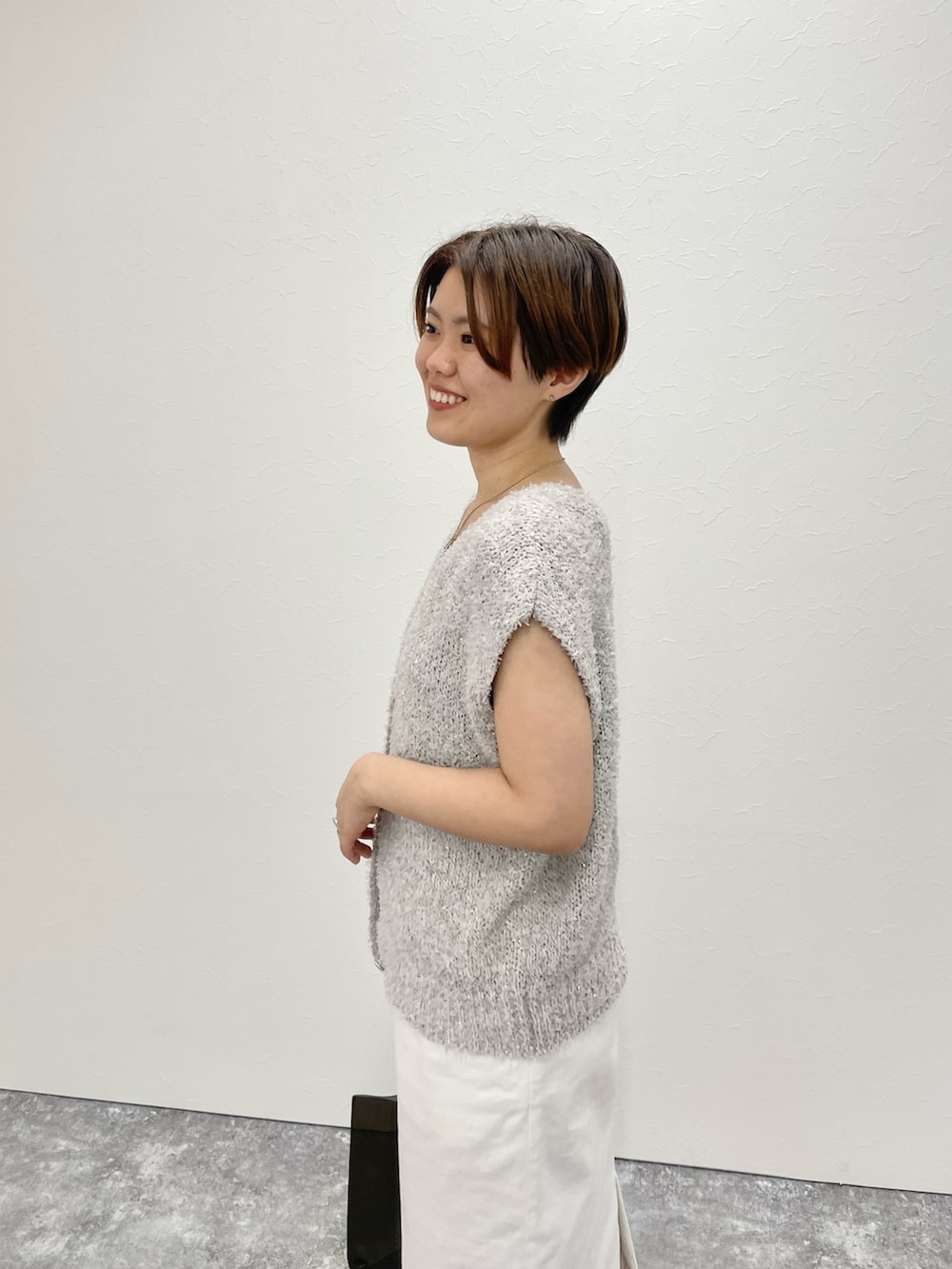 ベージュ系のベスト、ホワイト系のスカート、ブラック系のトートバッグを着用したレディースの春コーディネートの5枚目の写真