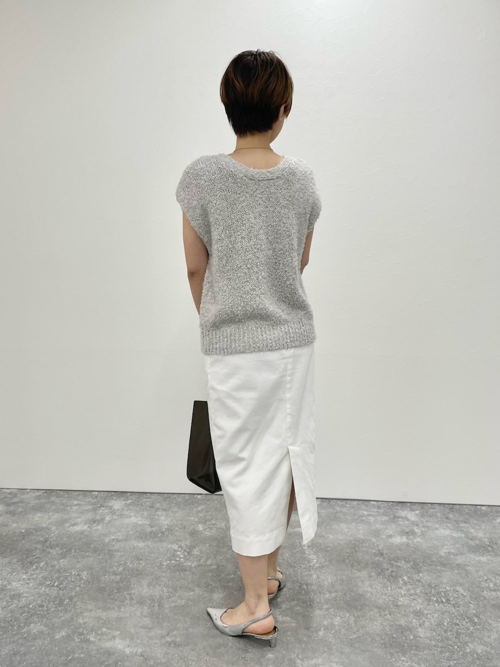 ベージュ系のベスト、ホワイト系のスカート、ブラック系のトートバッグを着用したレディースの春コーディネートの3枚目の写真