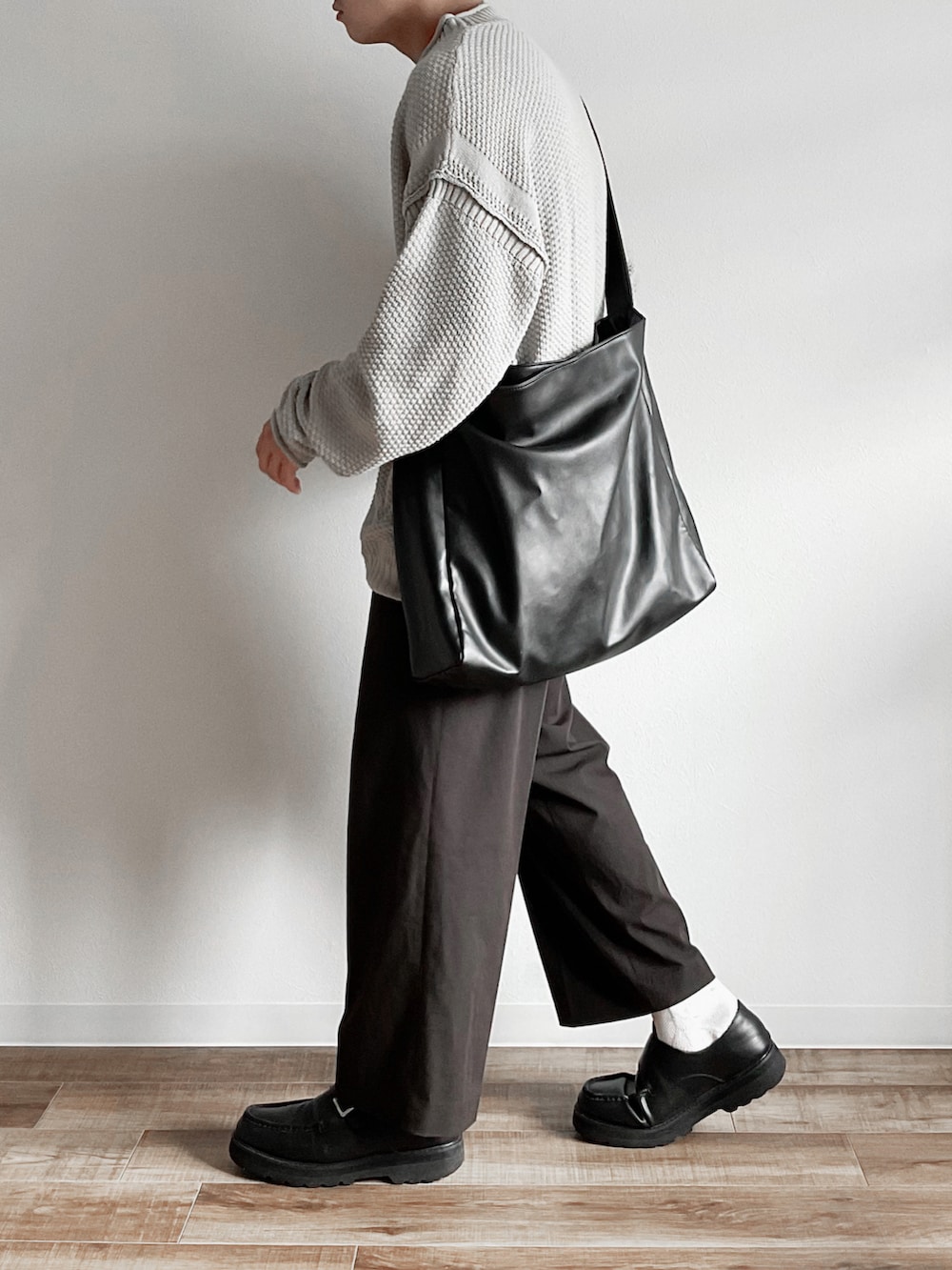 グレー系のニット/セーター、ブラウン系のパンツ、ブラック系のモカシン/デッキシューズを着用したメンズの秋コーディネートの3枚目の写真