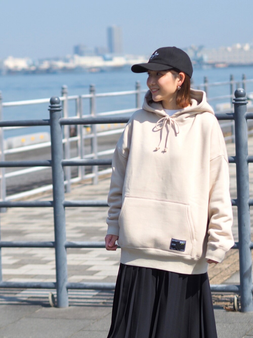 ベージュ系のパーカー、ブラック系のスカート、ベージュ系のスニーカーを着用したレディースの春コーディネートの2枚目の写真