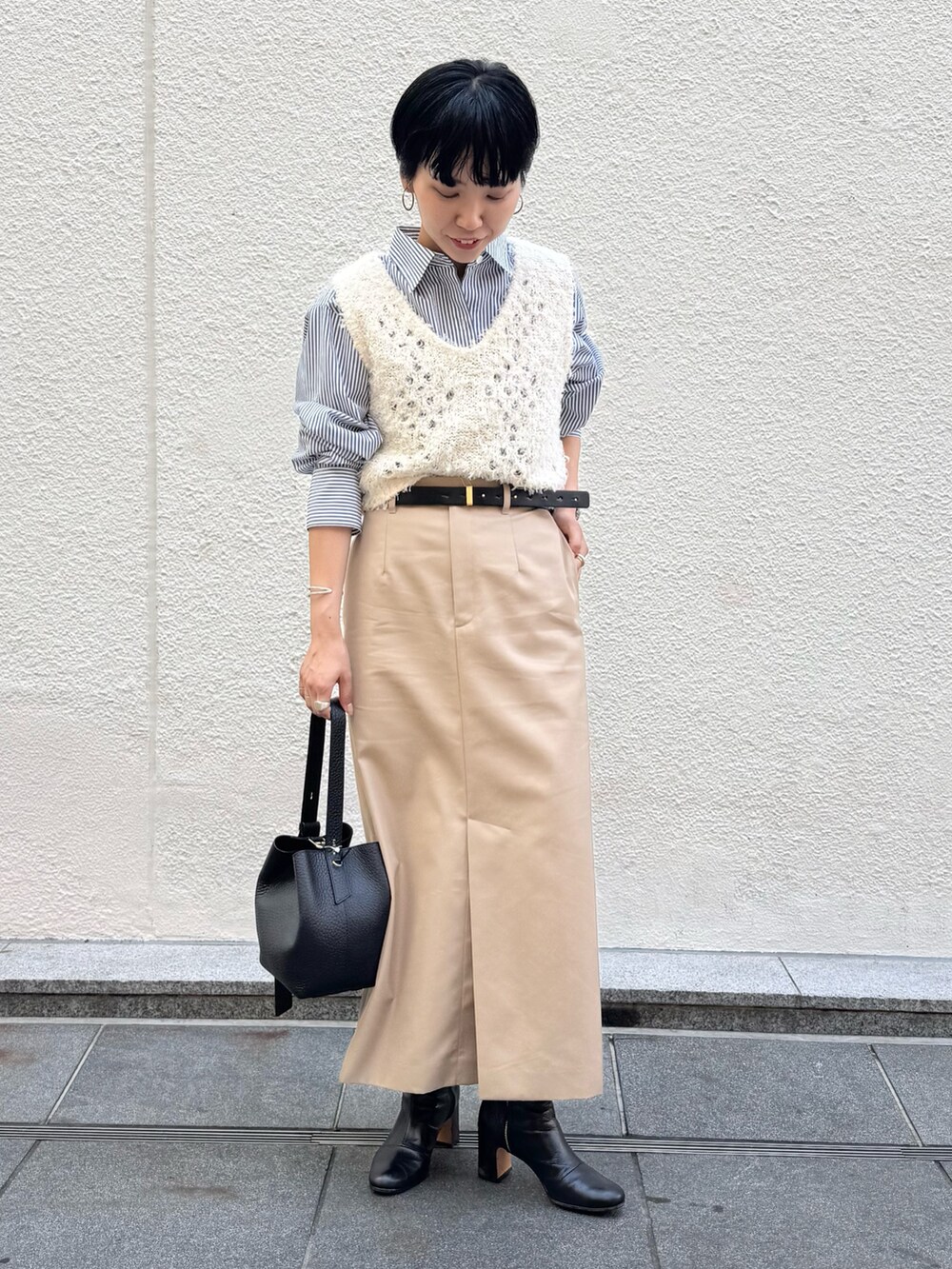ブルー系のシャツ/ブラウス、ホワイト系のベスト、ベージュ系のスカートを着用したレディースの秋コーディネートの2枚目の写真