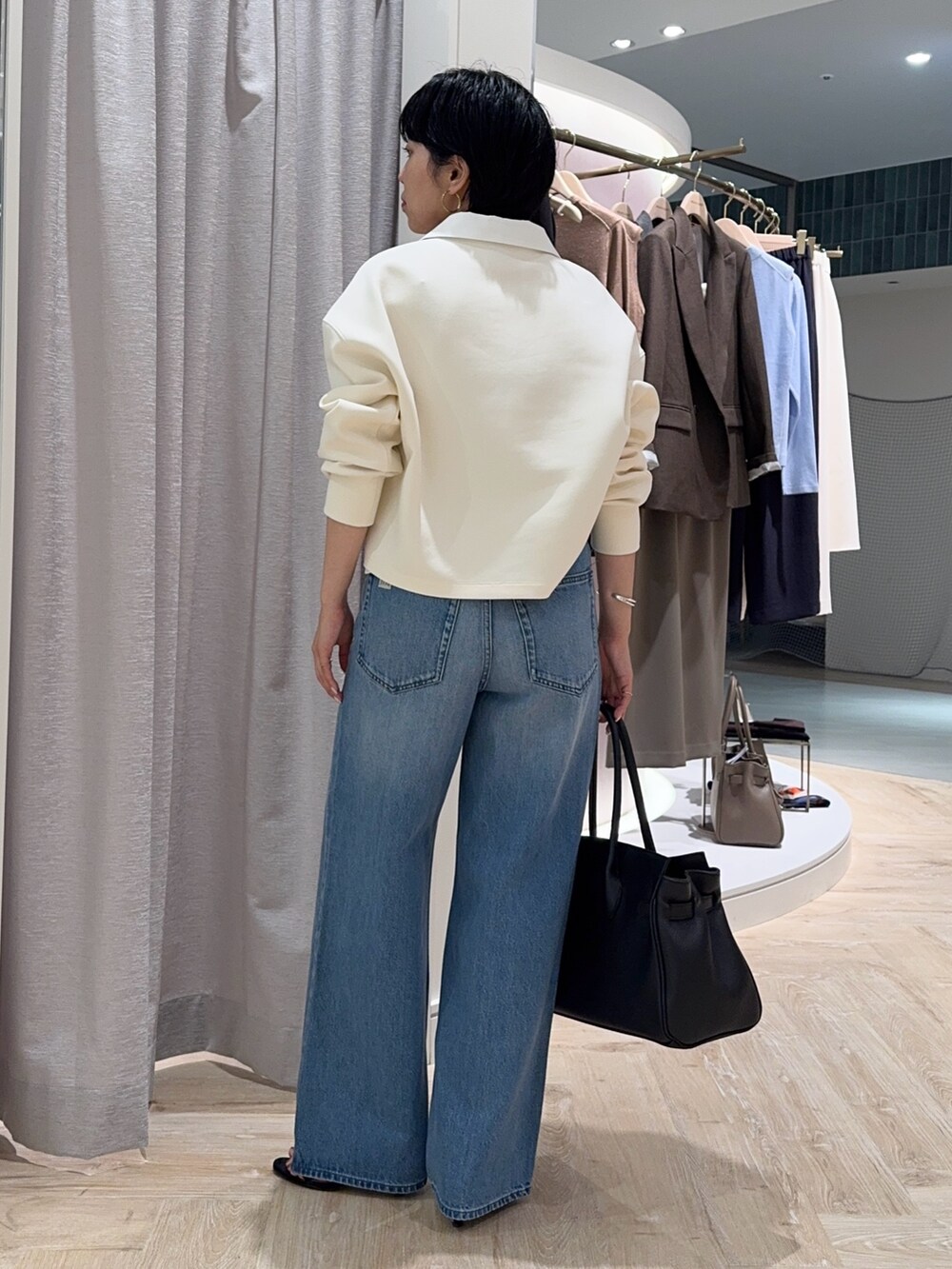 ブルー系のデニムパンツ、ブラック系のトートバッグ、ホワイト系のTシャツ/カットソーを着用したレディースの秋コーディネートの6枚目の写真