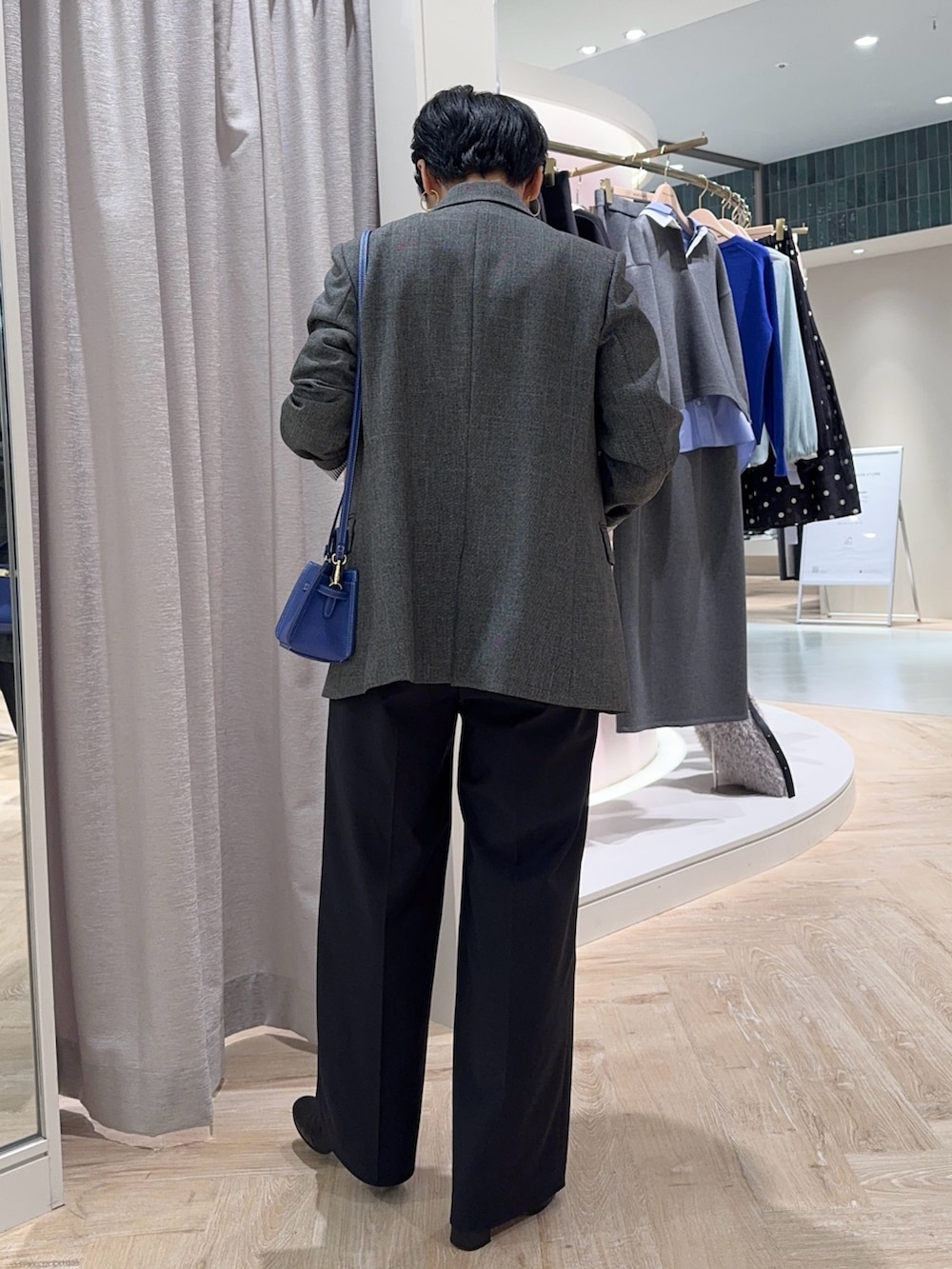 グレー系のテーラードジャケット、ブルー系のショルダーバッグ、ブルー系のニット/セーターを着用したレディースの秋コーディネートの4枚目の写真