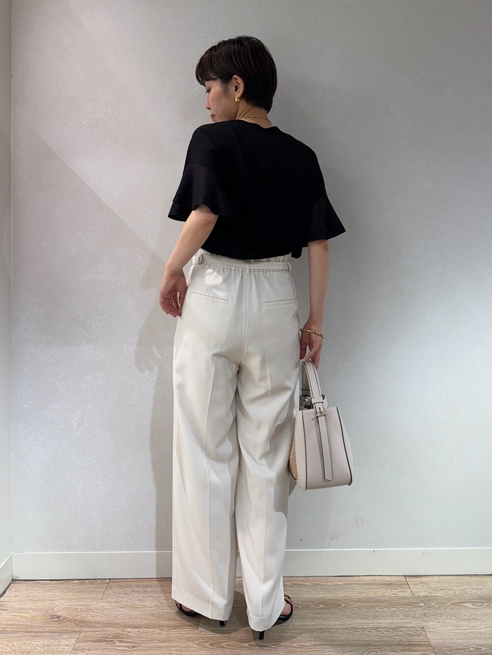 ブラック系のニット/セーター、ホワイト系のその他パンツ、ベージュ系のバックパック/リュックを着用したレディースの夏コーディネートの3枚目の写真