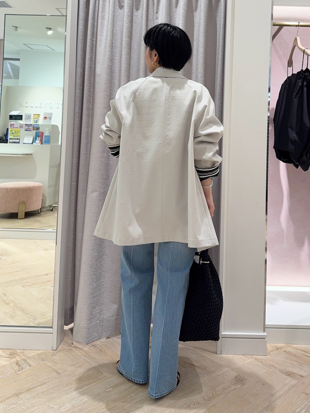 ブラック系のTシャツ/カットソー、ベージュ系のステンカラーコート、ブラック系のショルダーバッグを着用したレディースの春コーディネートの4枚目の写真