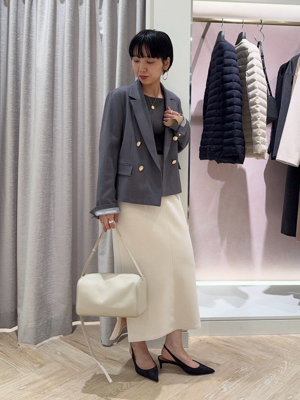 グレー系のニット/セーター、グレー系のテーラードジャケット、ホワイト系のスカートを着用したレディースの冬コーディネートの3枚目の写真