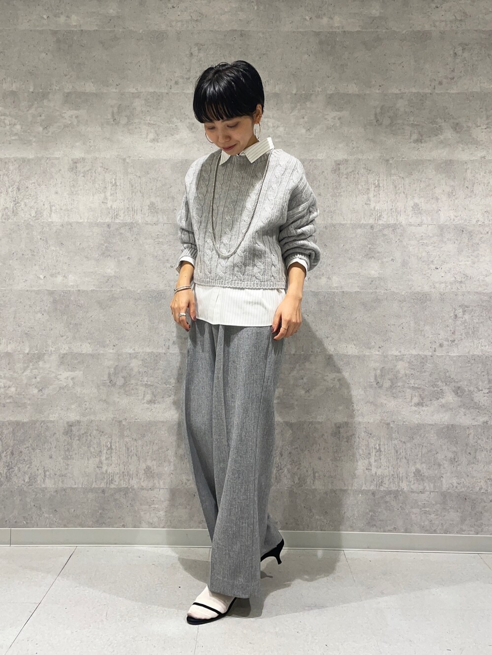 グレー系のその他パンツ、ホワイト系のシャツ/ブラウス、グレー系のニット/セーターを着用したレディースの秋コーディネートの3枚目の写真