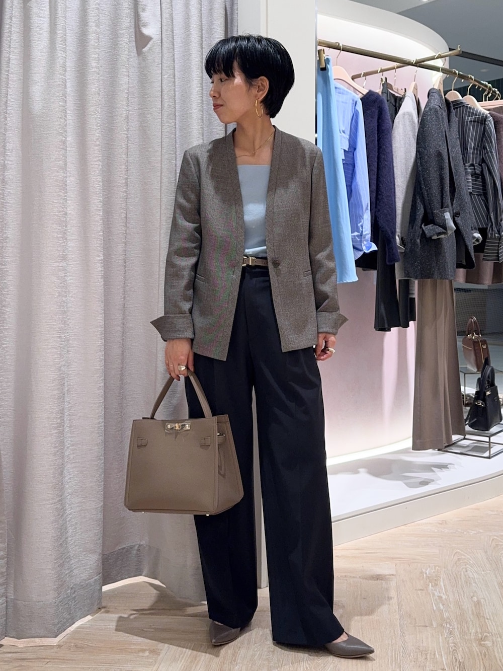 ブルー系のニット/セーター、ベージュ系のノーカラージャケット、ベージュ系のショルダーバッグを着用したレディースの秋コーディネートの5枚目の写真