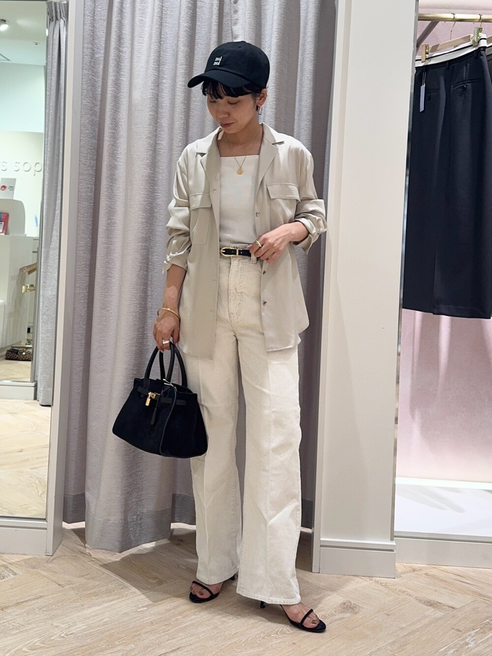 ブラック系のトートバッグ、ホワイト系のデニムパンツ、ホワイト系のタンクトップを着用したレディースの秋コーディネートの5枚目の写真