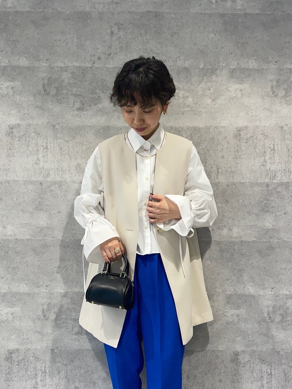 ブルー系のその他パンツ、ブラック系のボストンバッグ、ホワイト系のベストを着用したレディースの春コーディネートの4枚目の写真