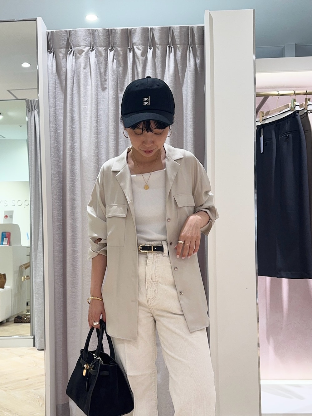 ブラック系のトートバッグ、ホワイト系のデニムパンツ、ホワイト系のタンクトップを着用したレディースの秋コーディネートの2枚目の写真