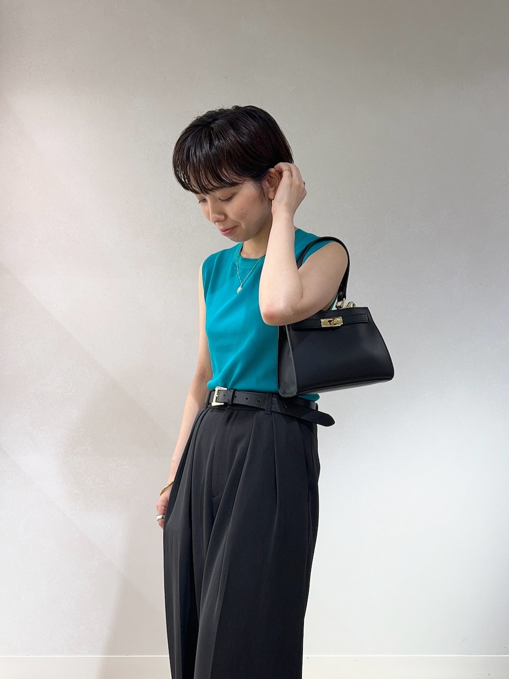 グリーン系のニット/セーター、グレー系のその他パンツ、ブラック系のベルトを着用したレディースの夏コーディネートの4枚目の写真