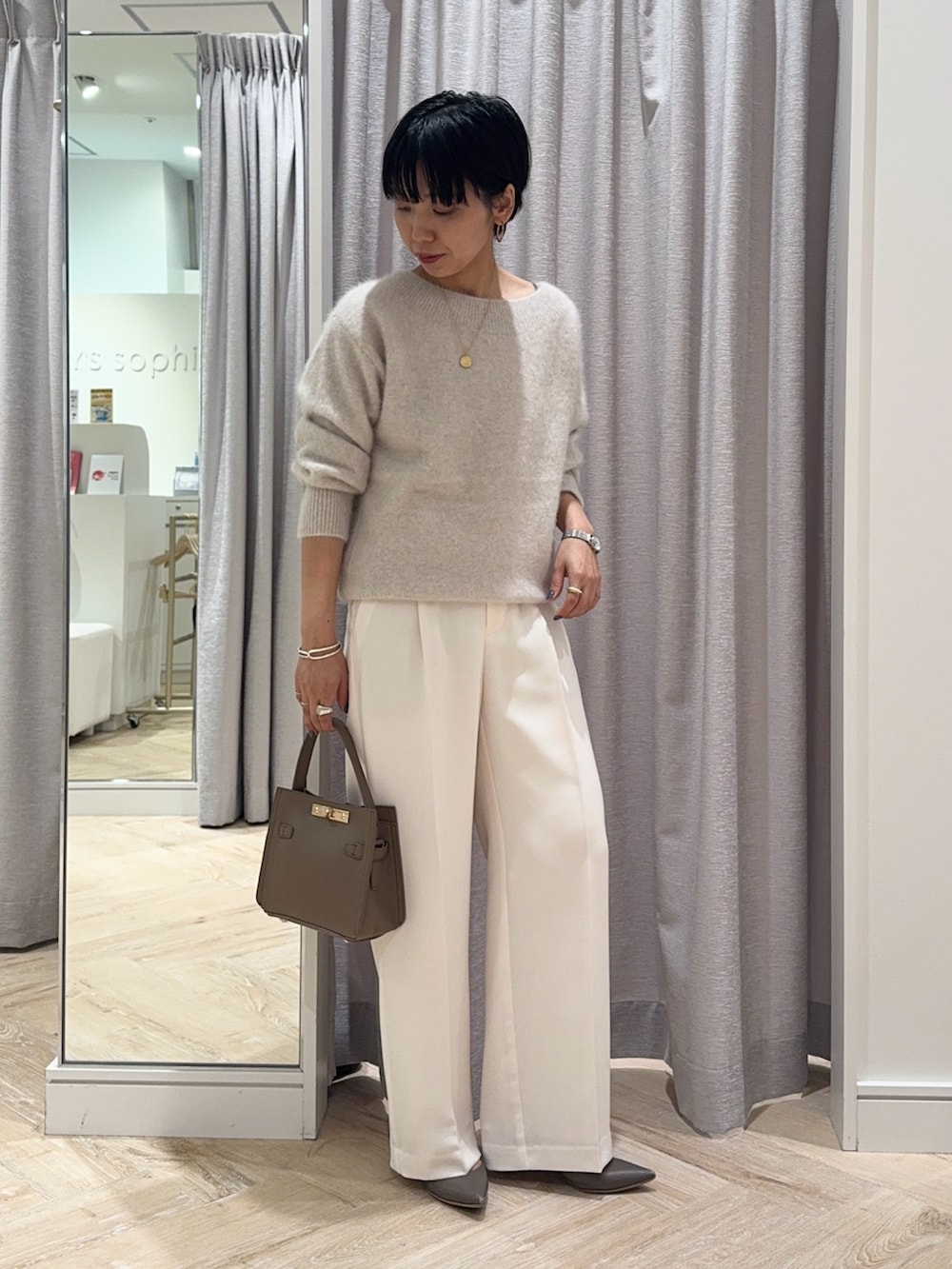 ベージュ系のニット/セーター、ベージュ系のショルダーバッグ、ホワイト系のその他パンツを着用したレディースの秋コーディネートの2枚目の写真