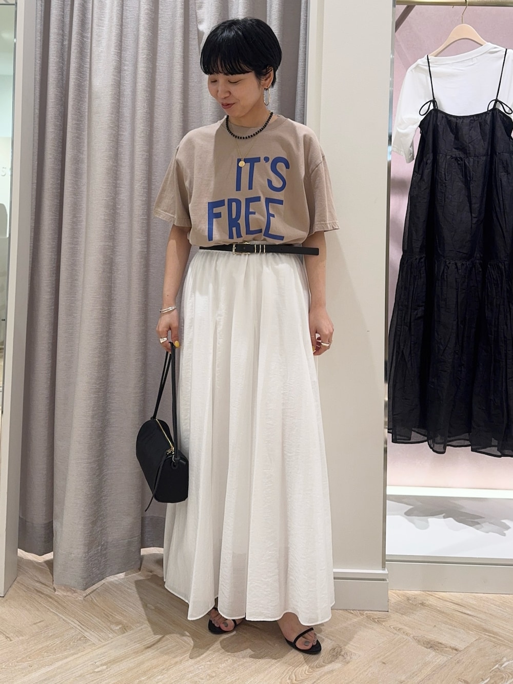 ベージュ系のTシャツ/カットソー、ホワイト系のスカート、ブラック系のショルダーバッグを着用したレディースの春コーディネートの4枚目の写真