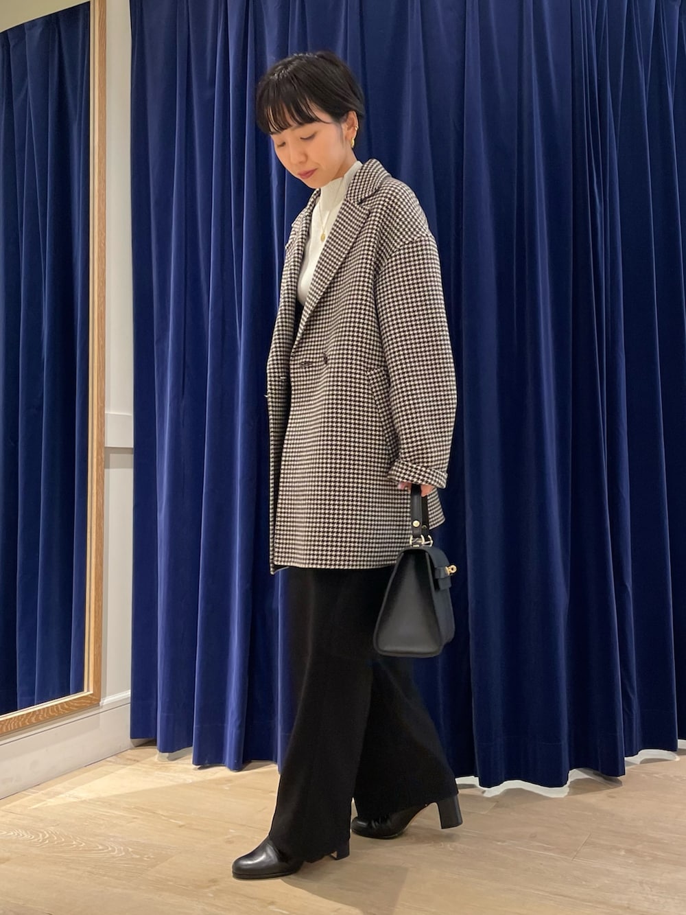 ベージュ系のチェスターコート、ホワイト系のニット/セーター、ブラック系のショルダーバッグを着用したレディースの冬コーディネートの2枚目の写真