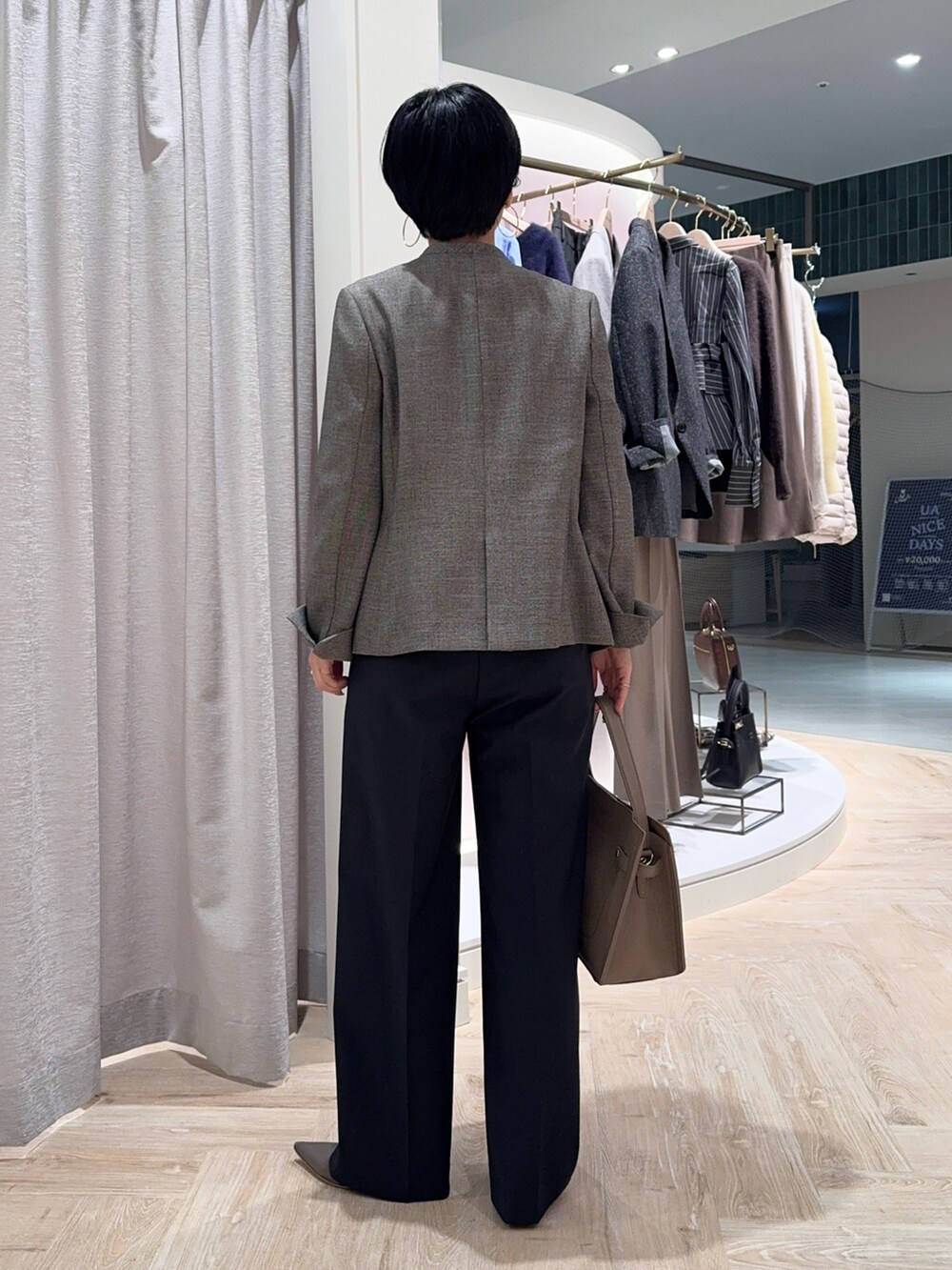 ブルー系のニット/セーター、ベージュ系のノーカラージャケット、ベージュ系のショルダーバッグを着用したレディースの秋コーディネートの4枚目の写真