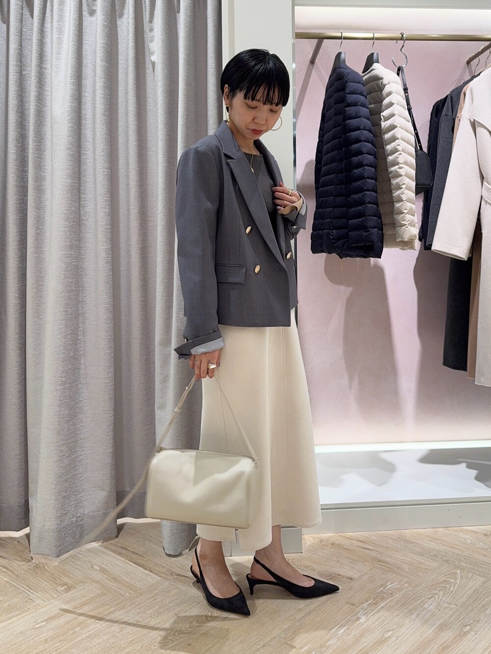 グレー系のニット/セーター、グレー系のテーラードジャケット、ホワイト系のスカートを着用したレディースの冬コーディネートの2枚目の写真