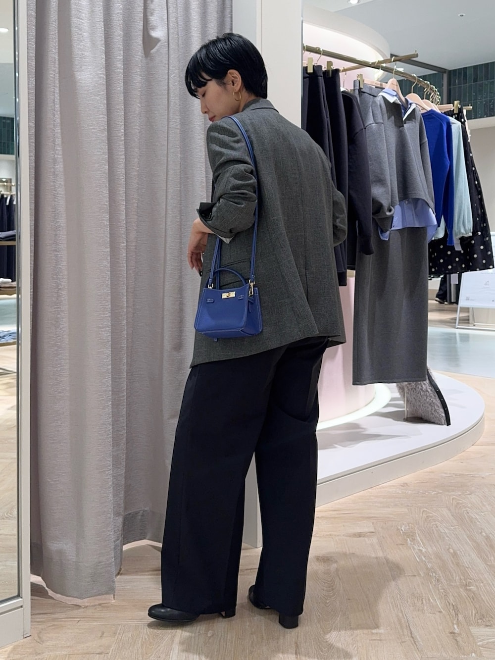 グレー系のテーラードジャケット、ブルー系のショルダーバッグ、ブルー系のニット/セーターを着用したレディースの秋コーディネートの2枚目の写真