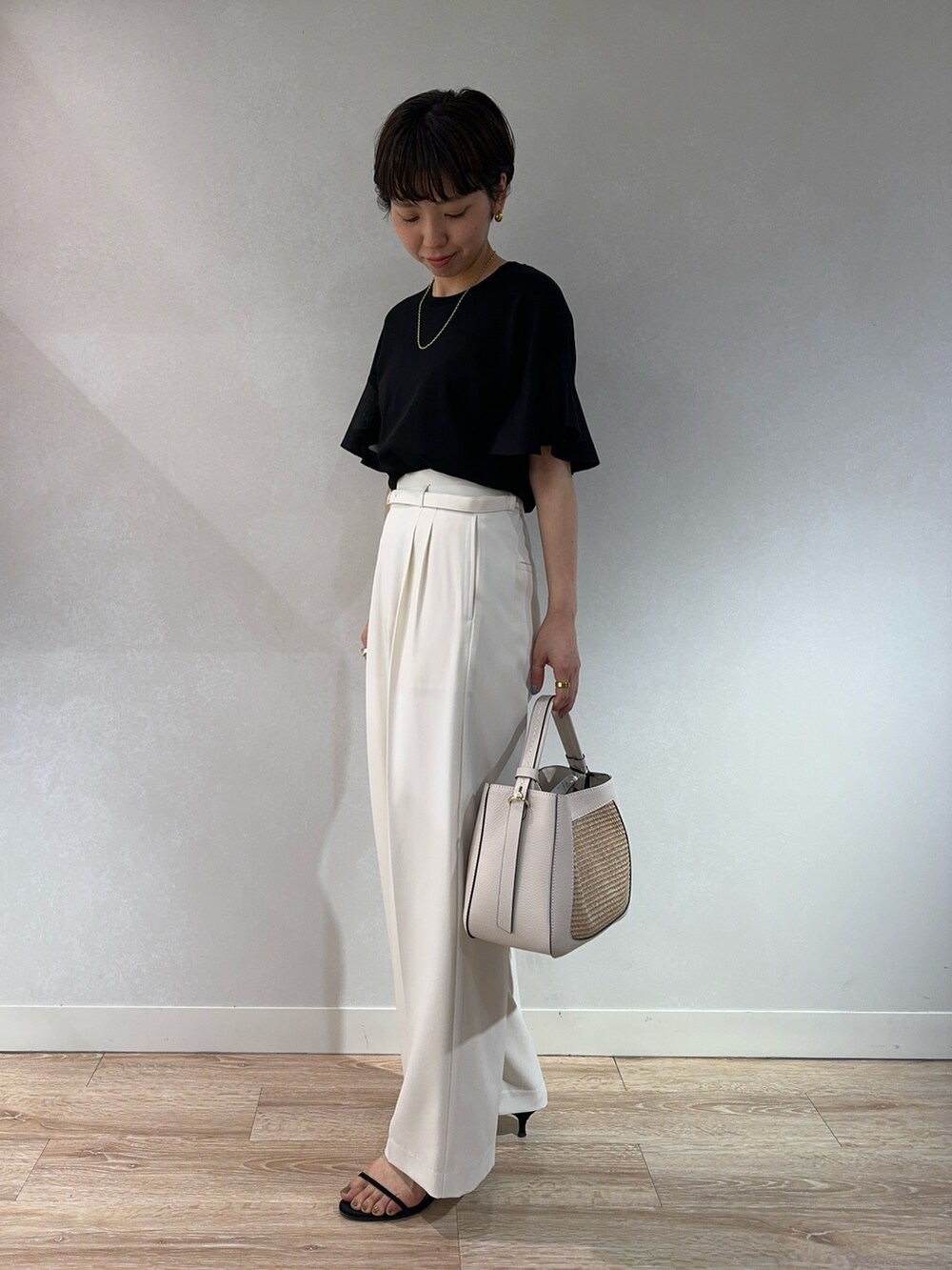 ブラック系のニット/セーター、ホワイト系のその他パンツ、ベージュ系のバックパック/リュックを着用したレディースの夏コーディネートの4枚目の写真