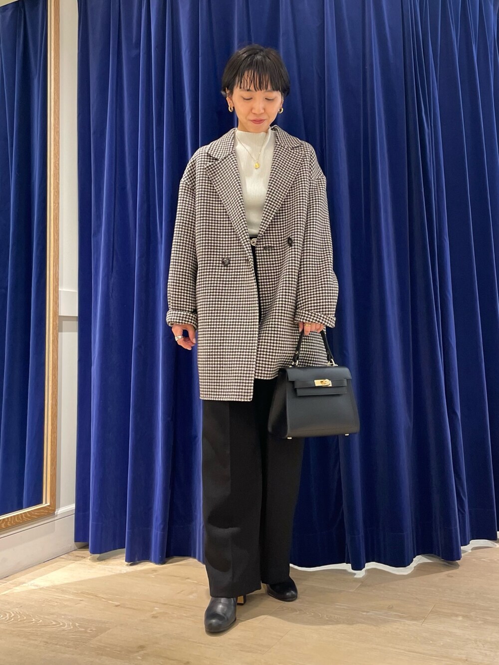 ベージュ系のチェスターコート、ホワイト系のニット/セーター、ブラック系のショルダーバッグを着用したレディースの冬コーディネートの4枚目の写真