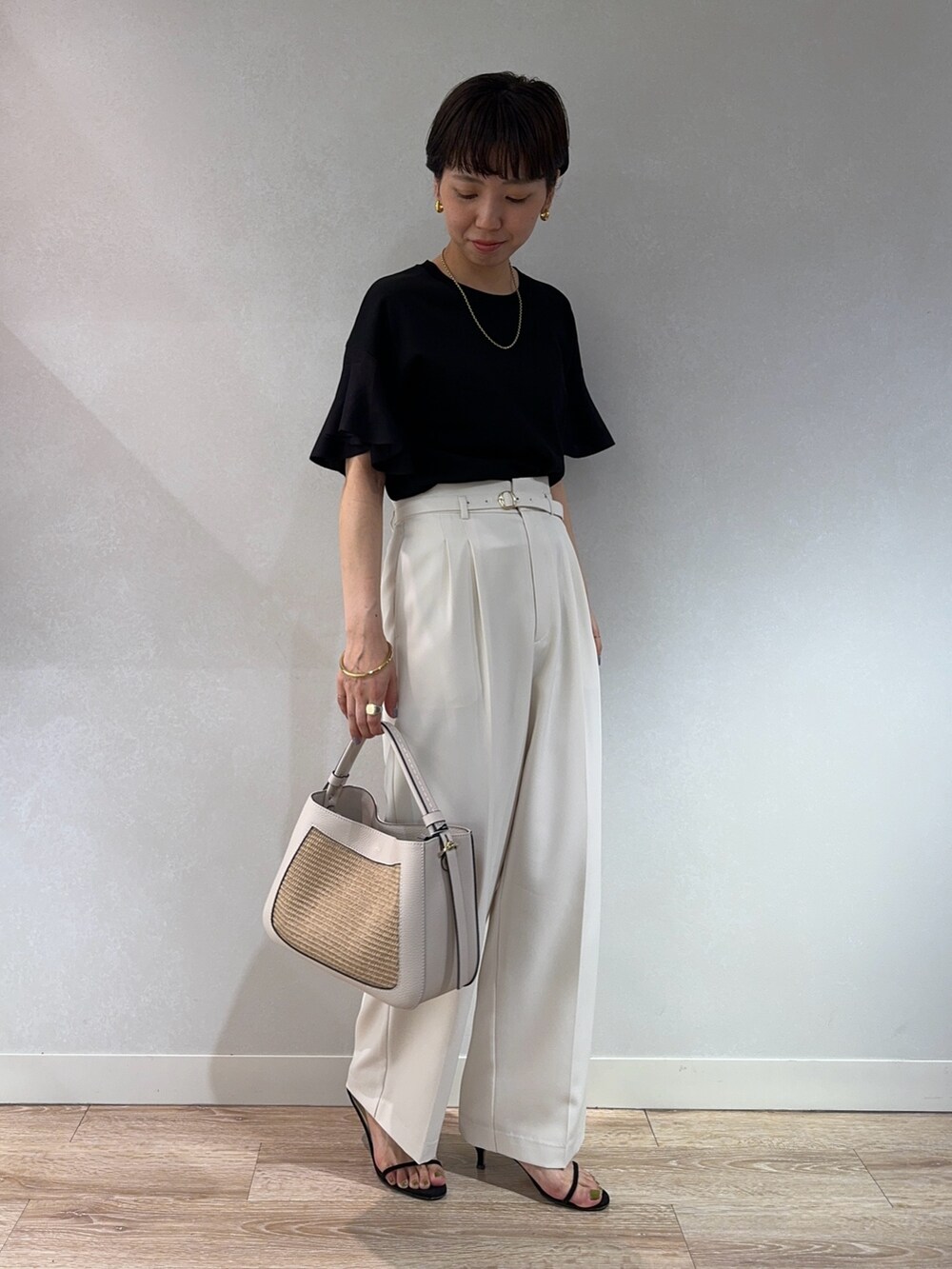 ブラック系のニット/セーター、ホワイト系のその他パンツ、ベージュ系のバックパック/リュックを着用したレディースの夏コーディネートの2枚目の写真