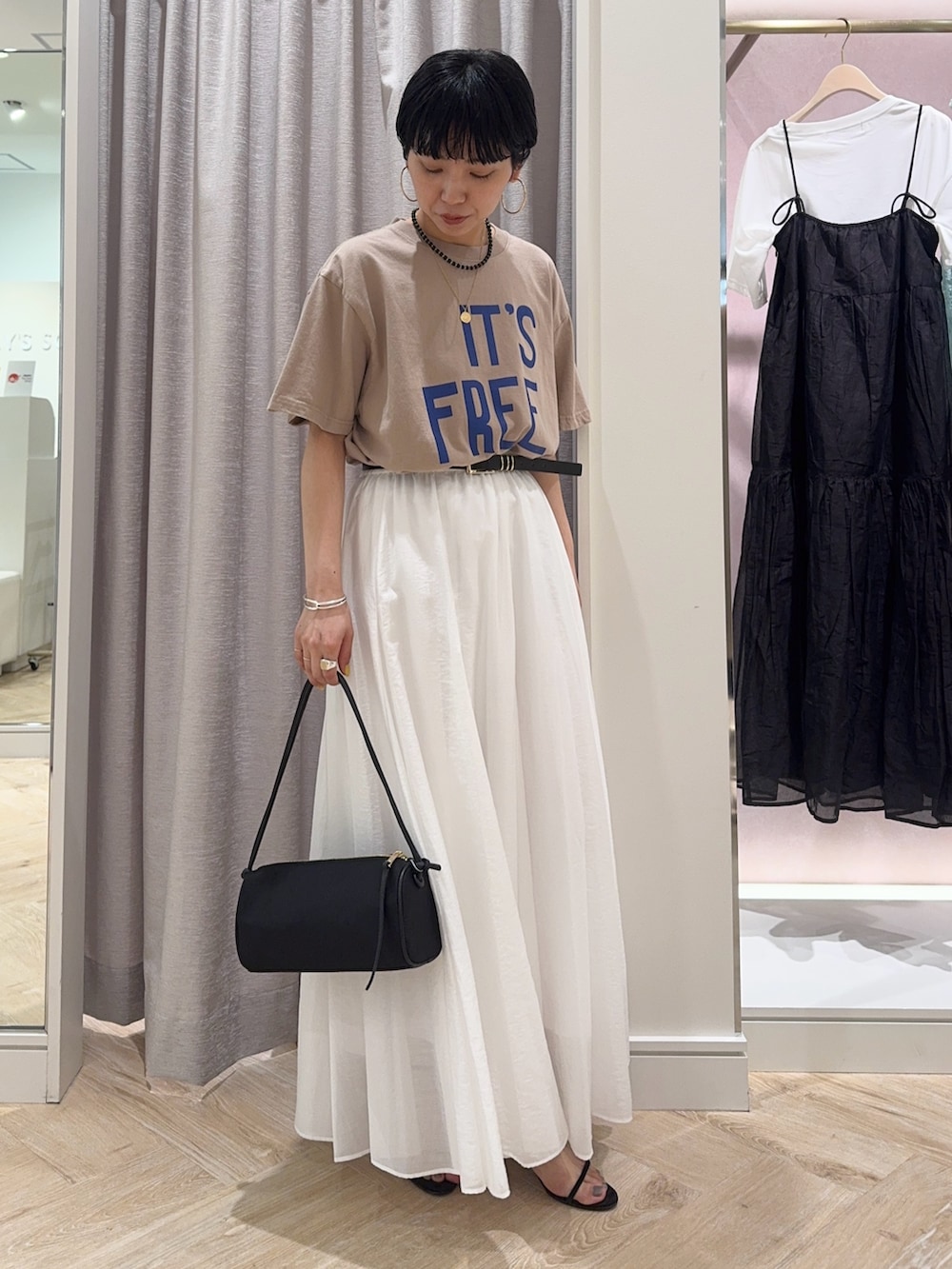 ベージュ系のTシャツ/カットソー、ホワイト系のスカート、ブラック系のショルダーバッグを着用したレディースの春コーディネートの2枚目の写真