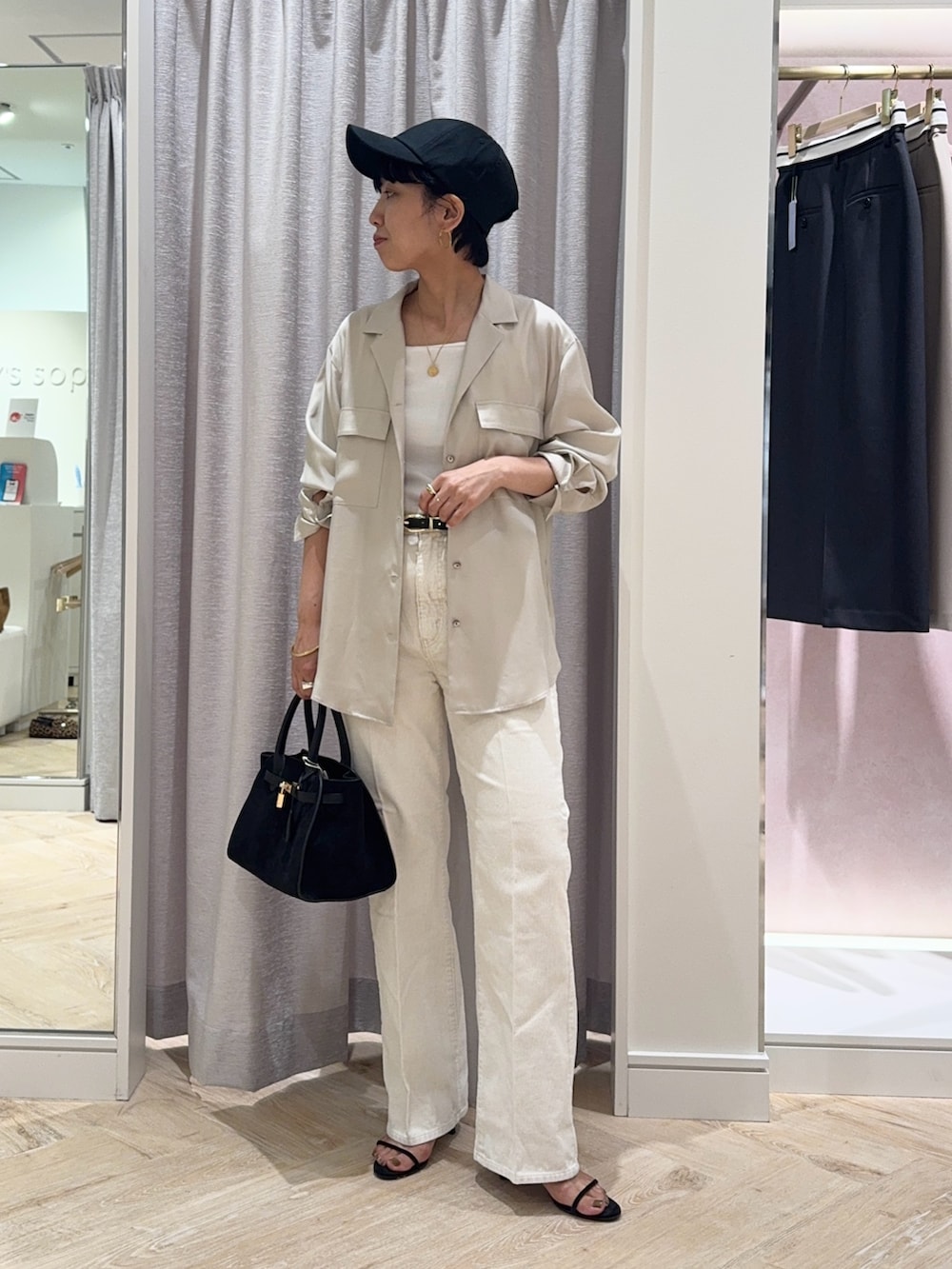 ブラック系のトートバッグ、ホワイト系のデニムパンツ、ホワイト系のタンクトップを着用したレディースの秋コーディネートの3枚目の写真