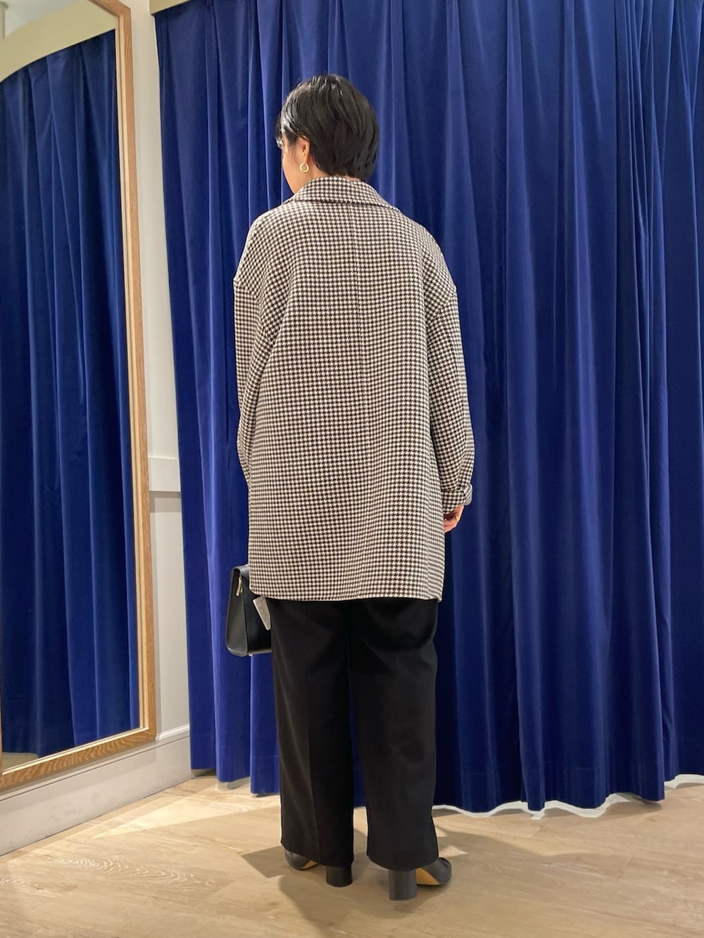 ベージュ系のチェスターコート、ホワイト系のニット/セーター、ブラック系のショルダーバッグを着用したレディースの冬コーディネートの3枚目の写真