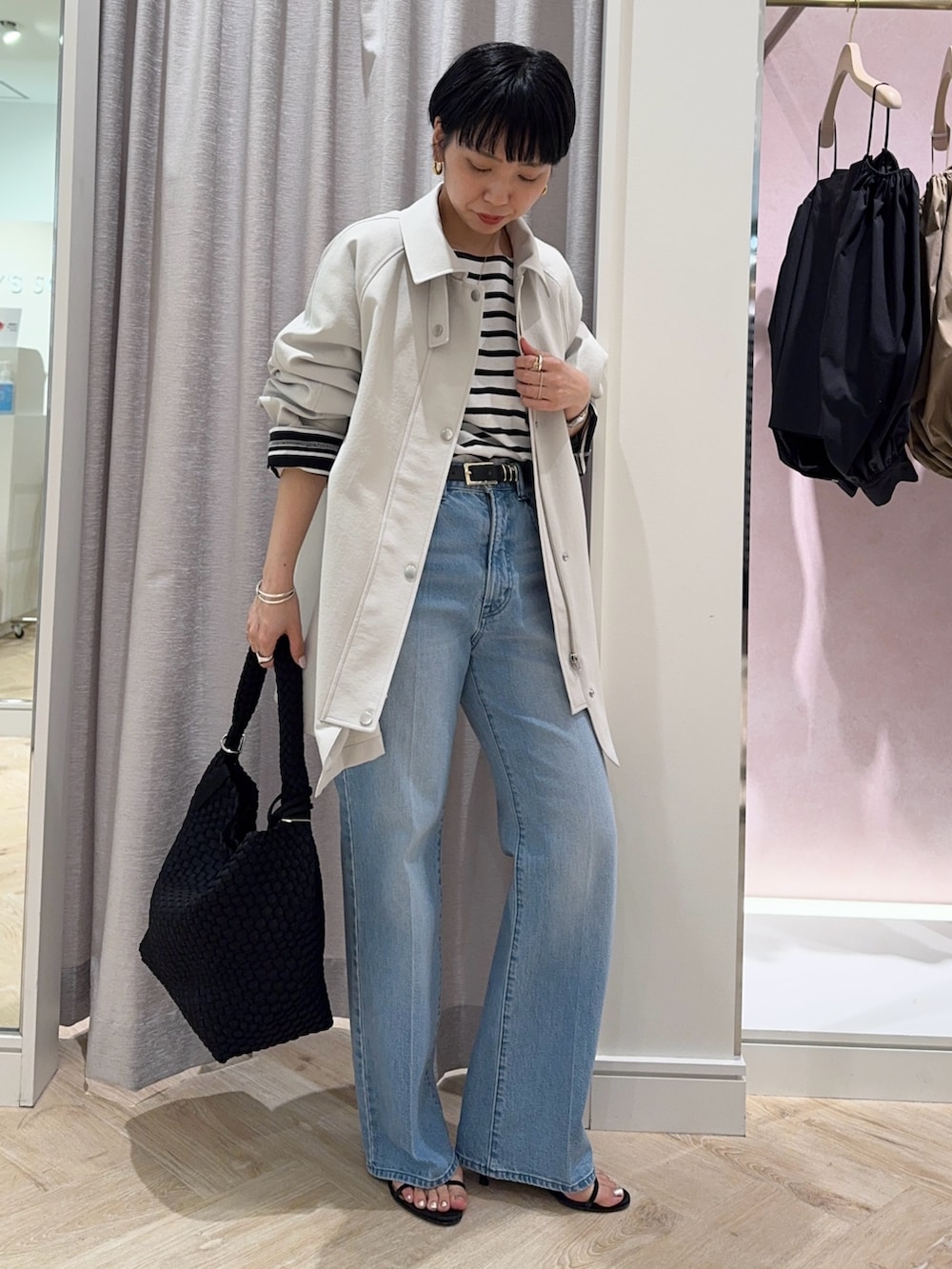 ブラック系のTシャツ/カットソー、ベージュ系のステンカラーコート、ブラック系のショルダーバッグを着用したレディースの春コーディネートの3枚目の写真