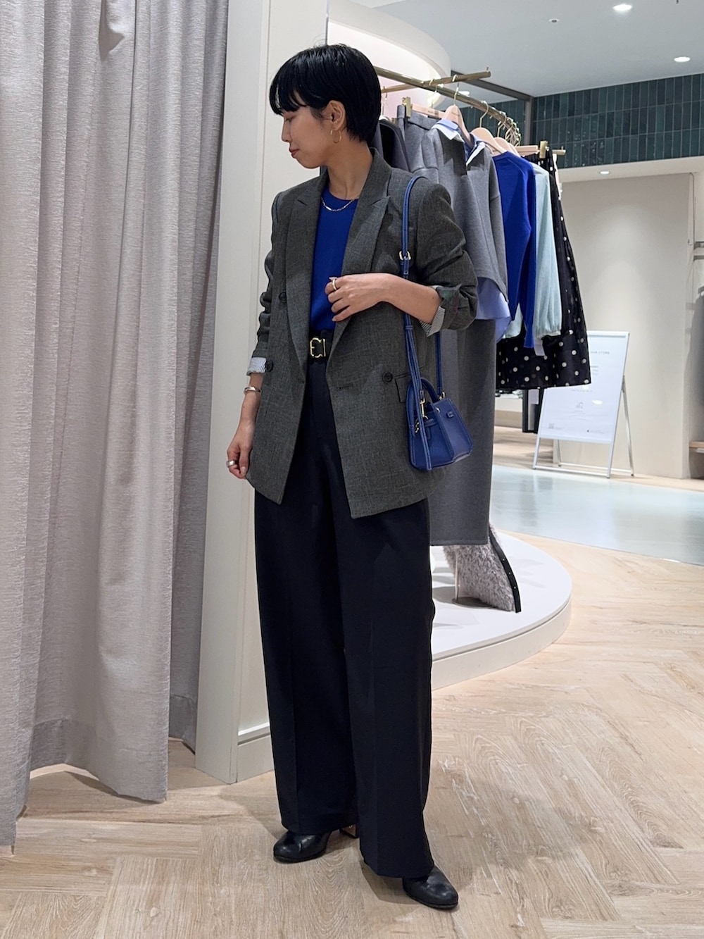 グレー系のテーラードジャケット、ブルー系のショルダーバッグ、ブルー系のニット/セーターを着用したレディースの秋コーディネートの3枚目の写真