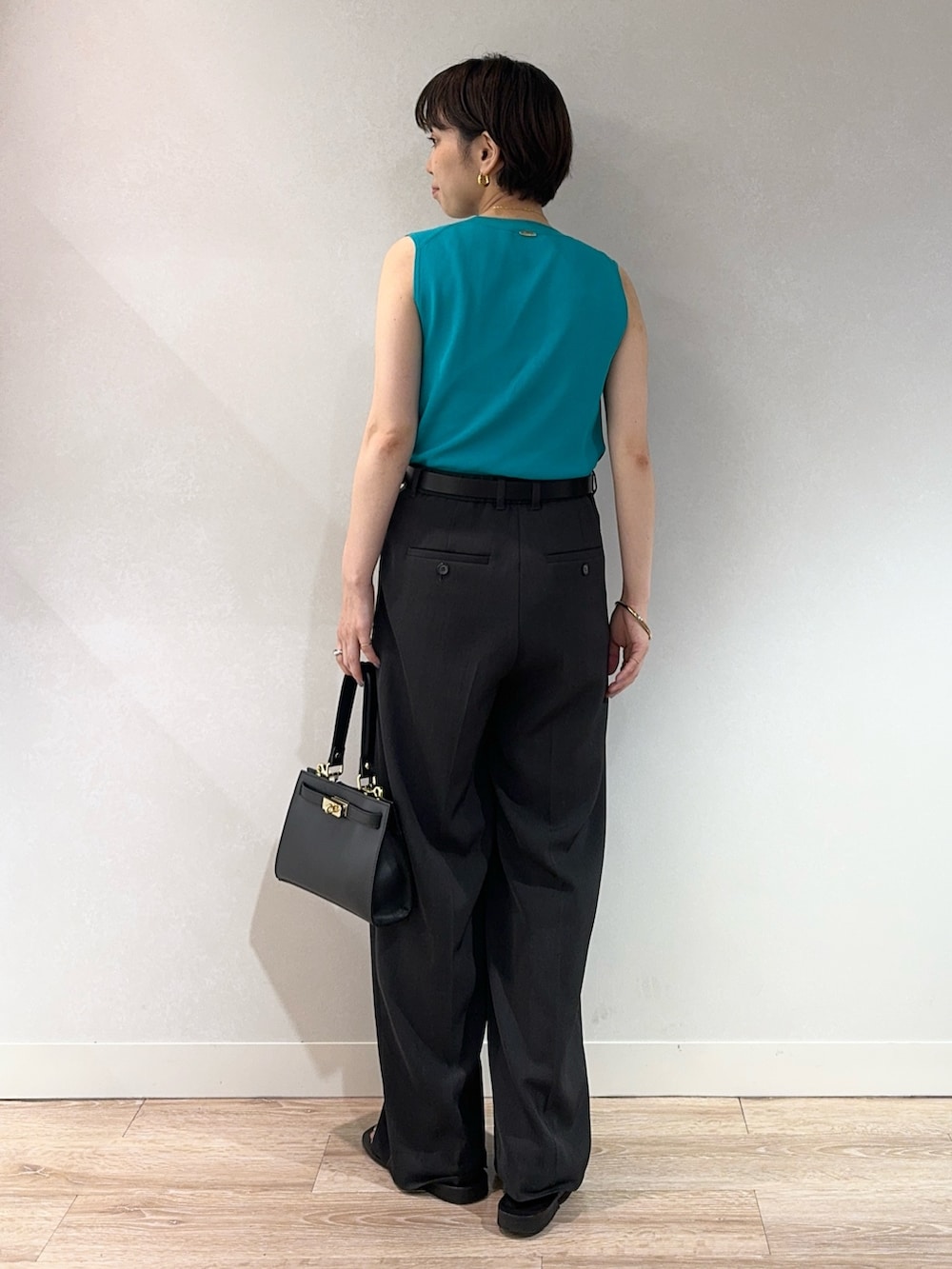 グリーン系のニット/セーター、グレー系のその他パンツ、ブラック系のベルトを着用したレディースの夏コーディネートの2枚目の写真