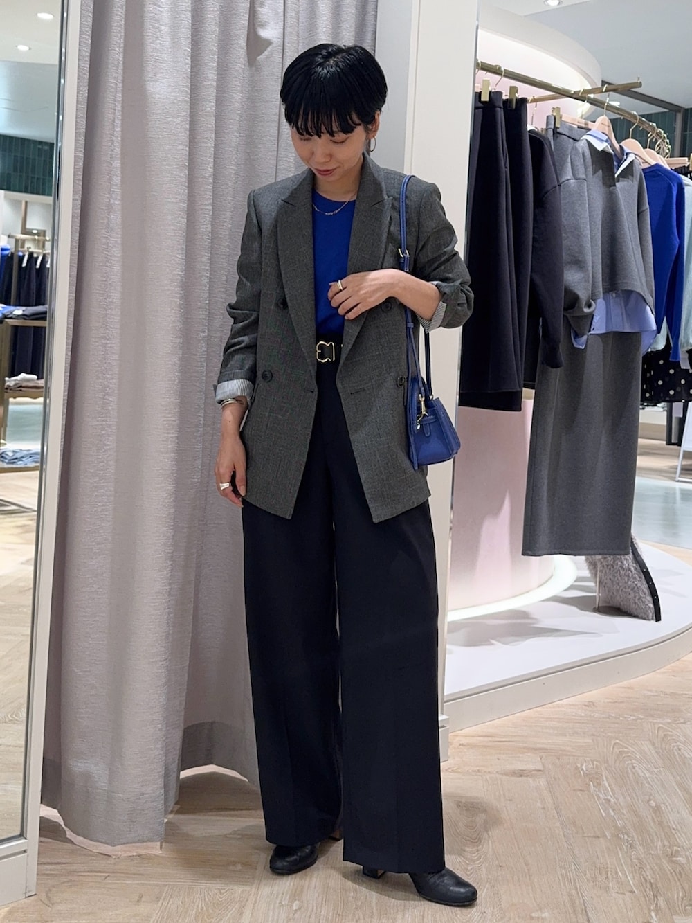 グレー系のテーラードジャケット、ブルー系のショルダーバッグ、ブルー系のニット/セーターを着用したレディースの秋コーディネートの5枚目の写真