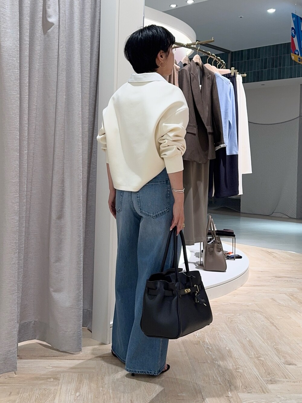 ブルー系のデニムパンツ、ブラック系のトートバッグ、ホワイト系のTシャツ/カットソーを着用したレディースの秋コーディネートの5枚目の写真