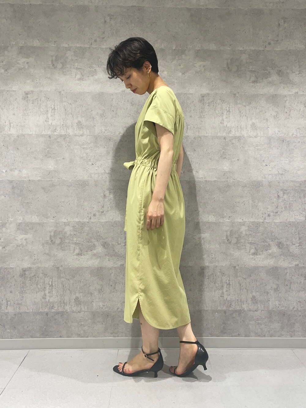 ブラック系のカーディガン/ボレロ、ブラック系のサンダル、イエロー系のワンピースを着用したレディースの夏コーディネートの2枚目の写真